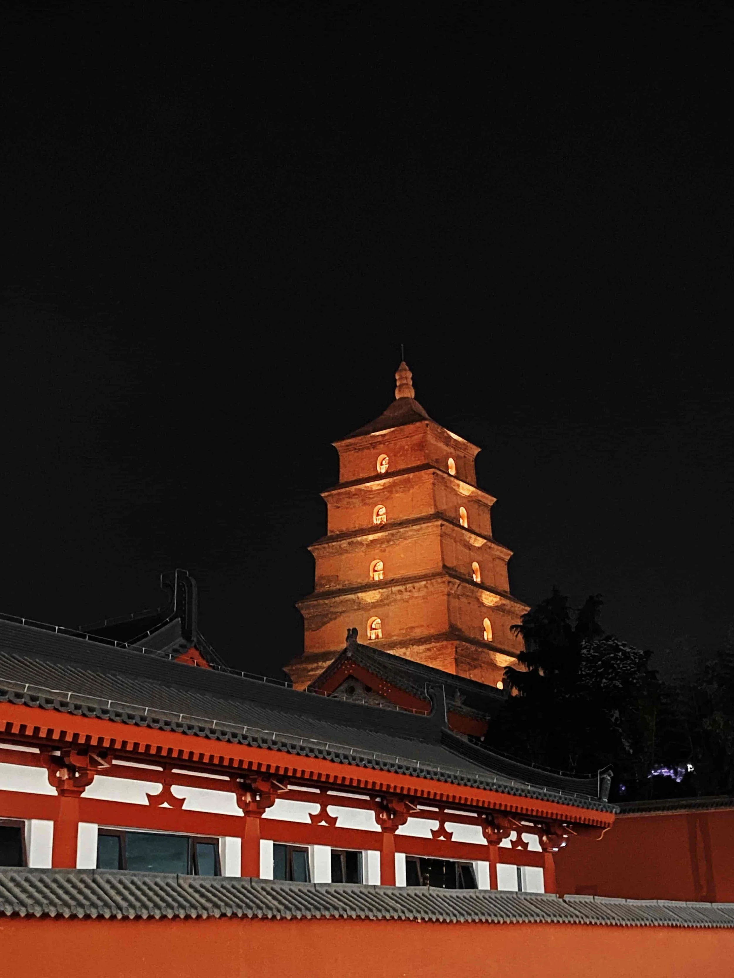 A mountain peak with temples and structures built on top, surrounded by trees and snow, under a clear blue sky.
