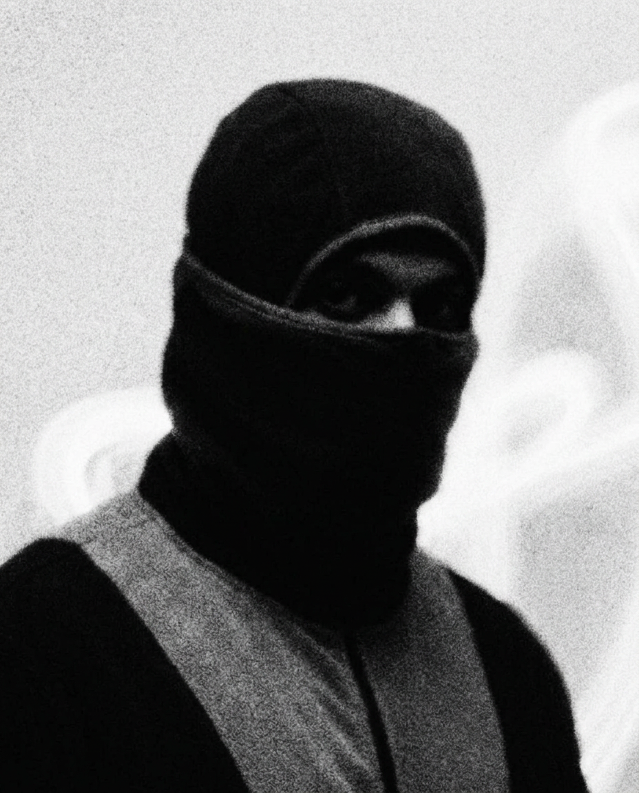Person wearing a mask and scarf covering the face, with only eyes visible, in black and white.