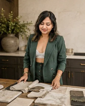 Woman in green blazer looking at marble and tile samples in a kitchen showroom.