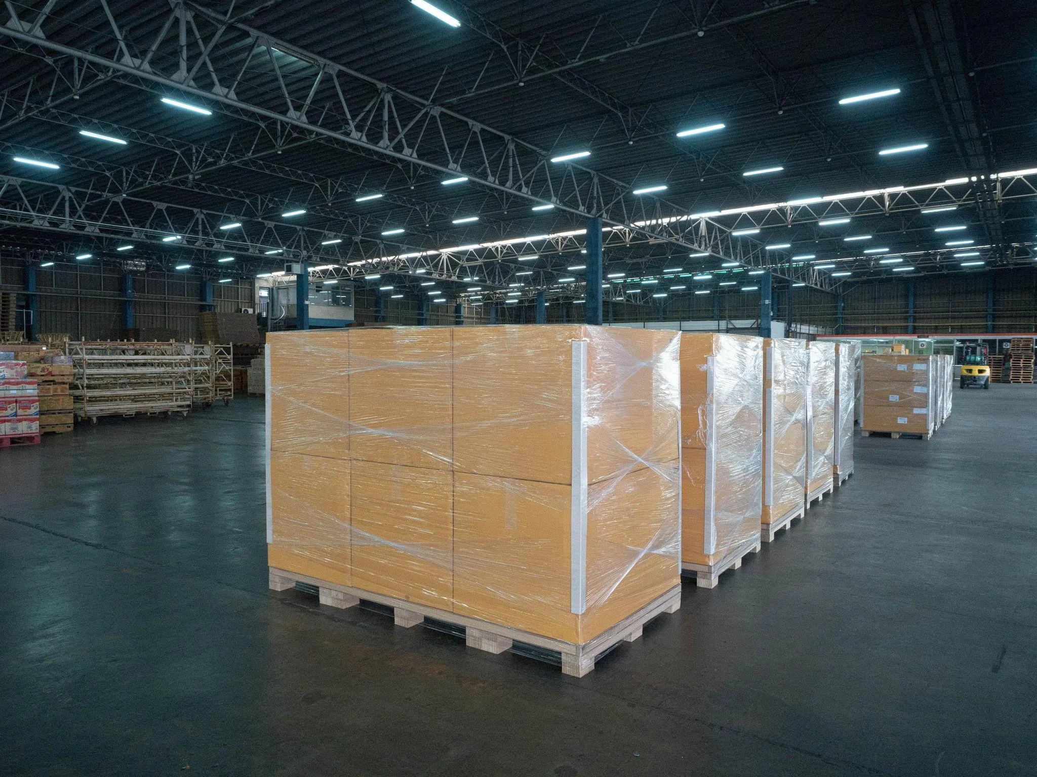 Interior of a large warehouse with stacks of wrapped pallets and bright overhead lighting.