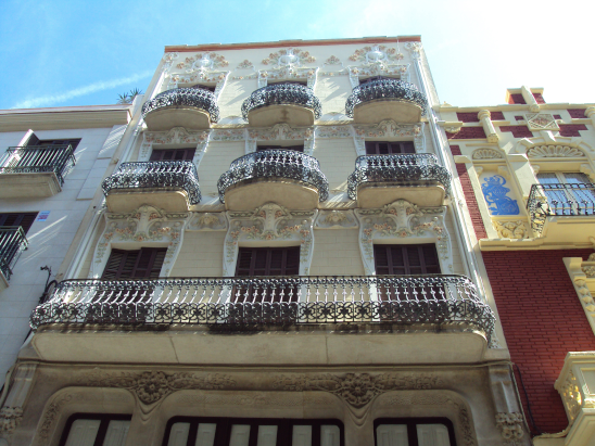Edificio de múltiples pisos con balcones de hierro forjado y decoración ornamental en la fachada