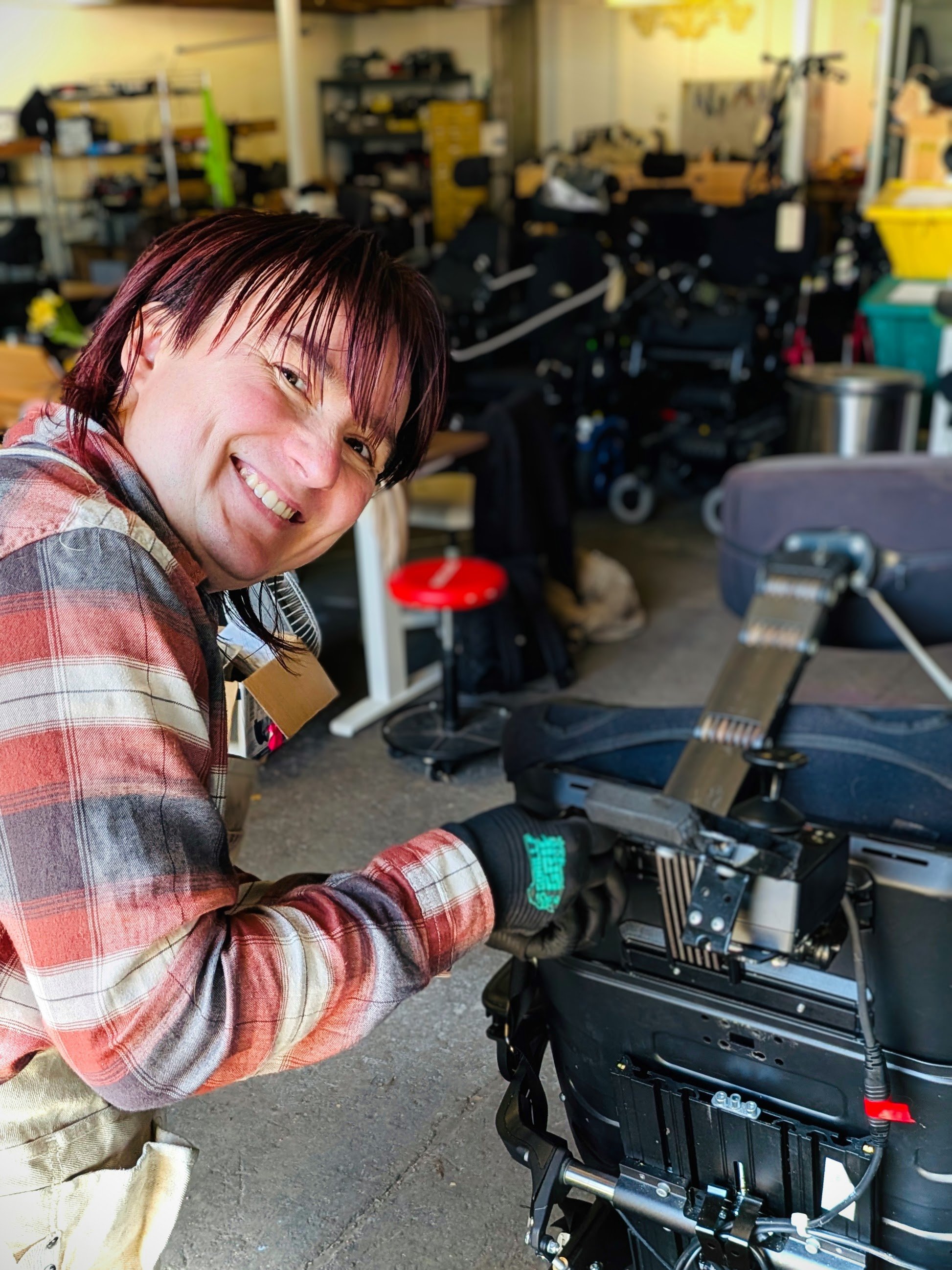Olga smiling at the camera while working on a power wheelchair