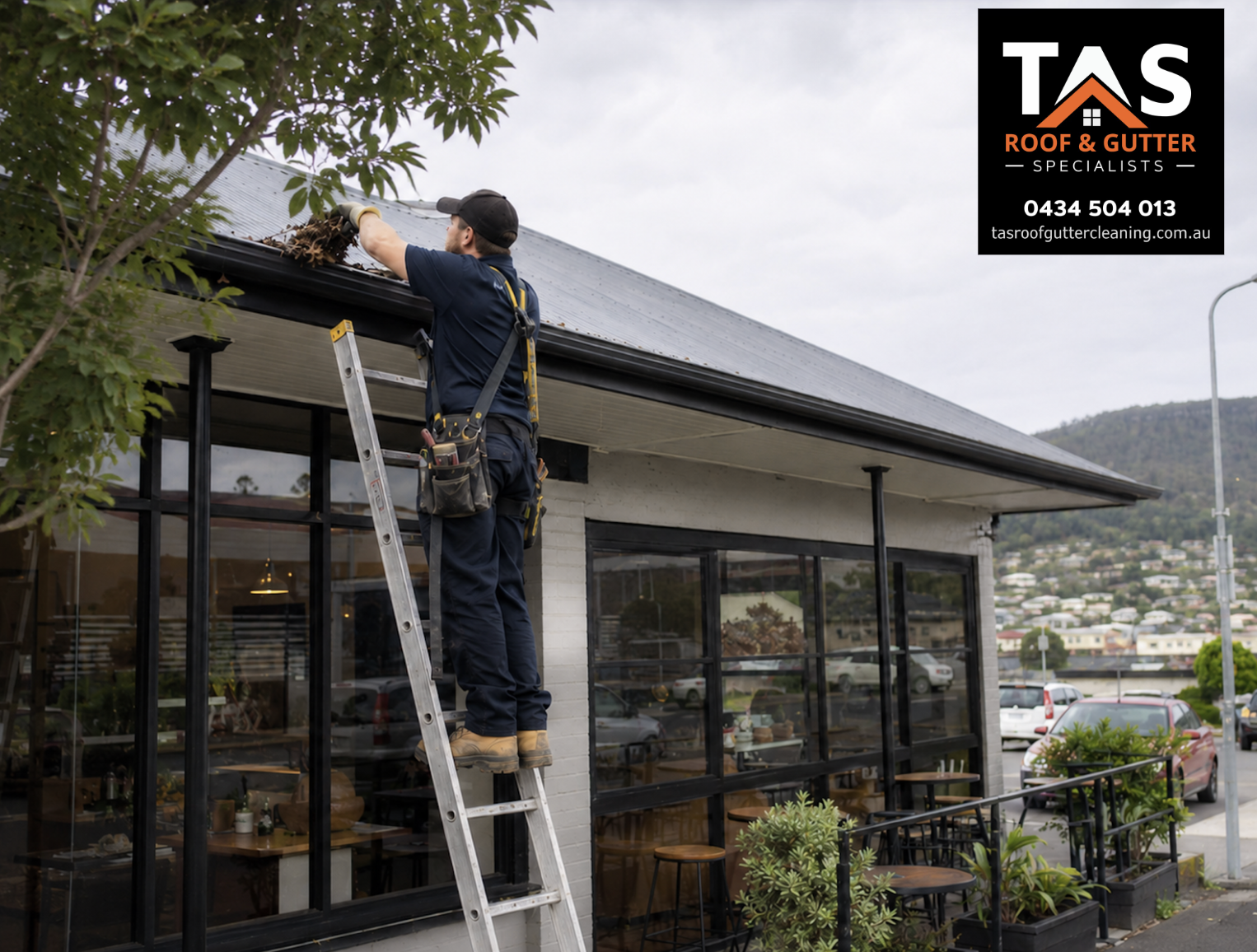 Commercial gutter cleaning in Burnie with technician clearing leaves from a shop or cafe roofline