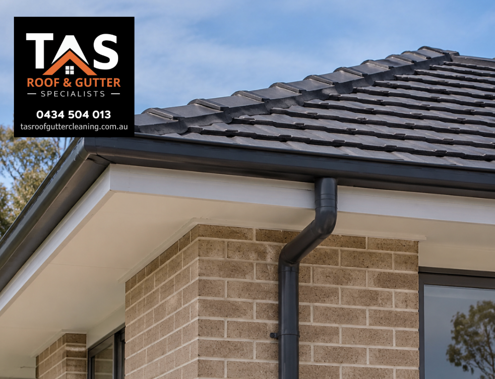 Residential eaves gutter and connected downpipe installed along the roof edge of a Hobart brick home.