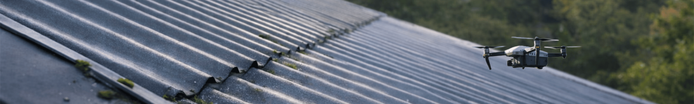 A drone inspect a metal roof with some moss and debris on it, with green trees in the background in Hobart, Tasmania