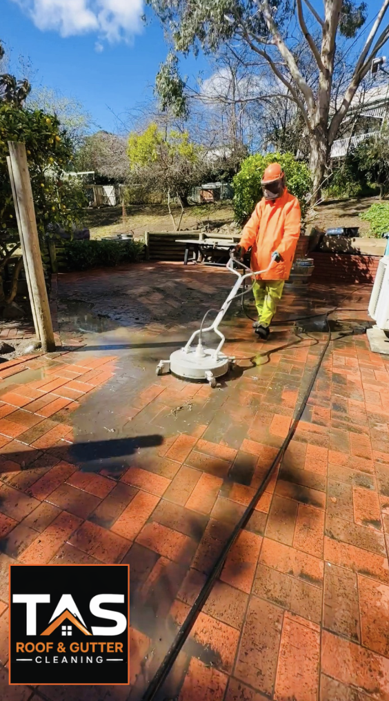 Pressure cleaning a red brick patio in Hobart, showing the contrast between cleaned and dirty pavers.
