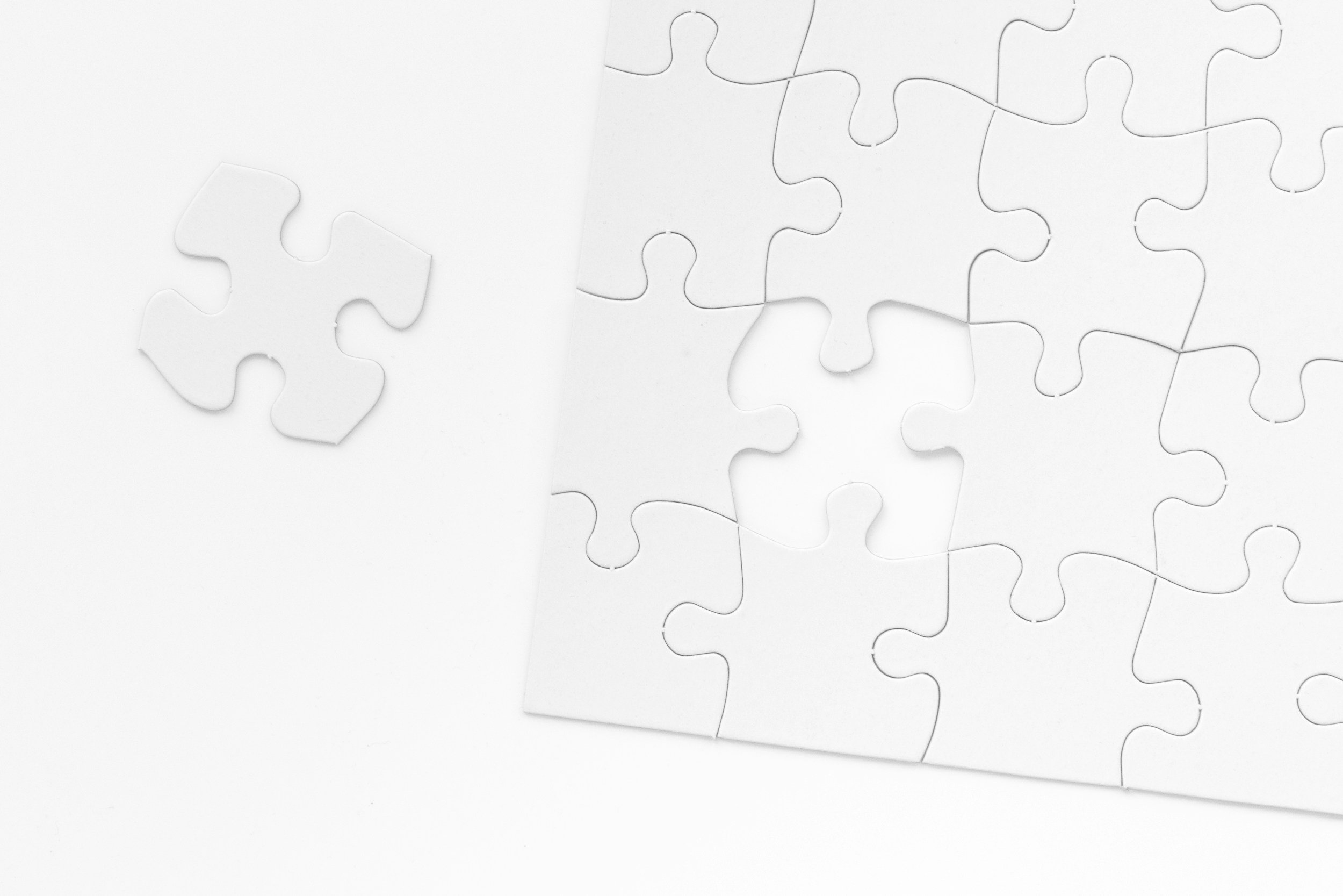 A partially assembled white jigsaw puzzle with one loose piece.