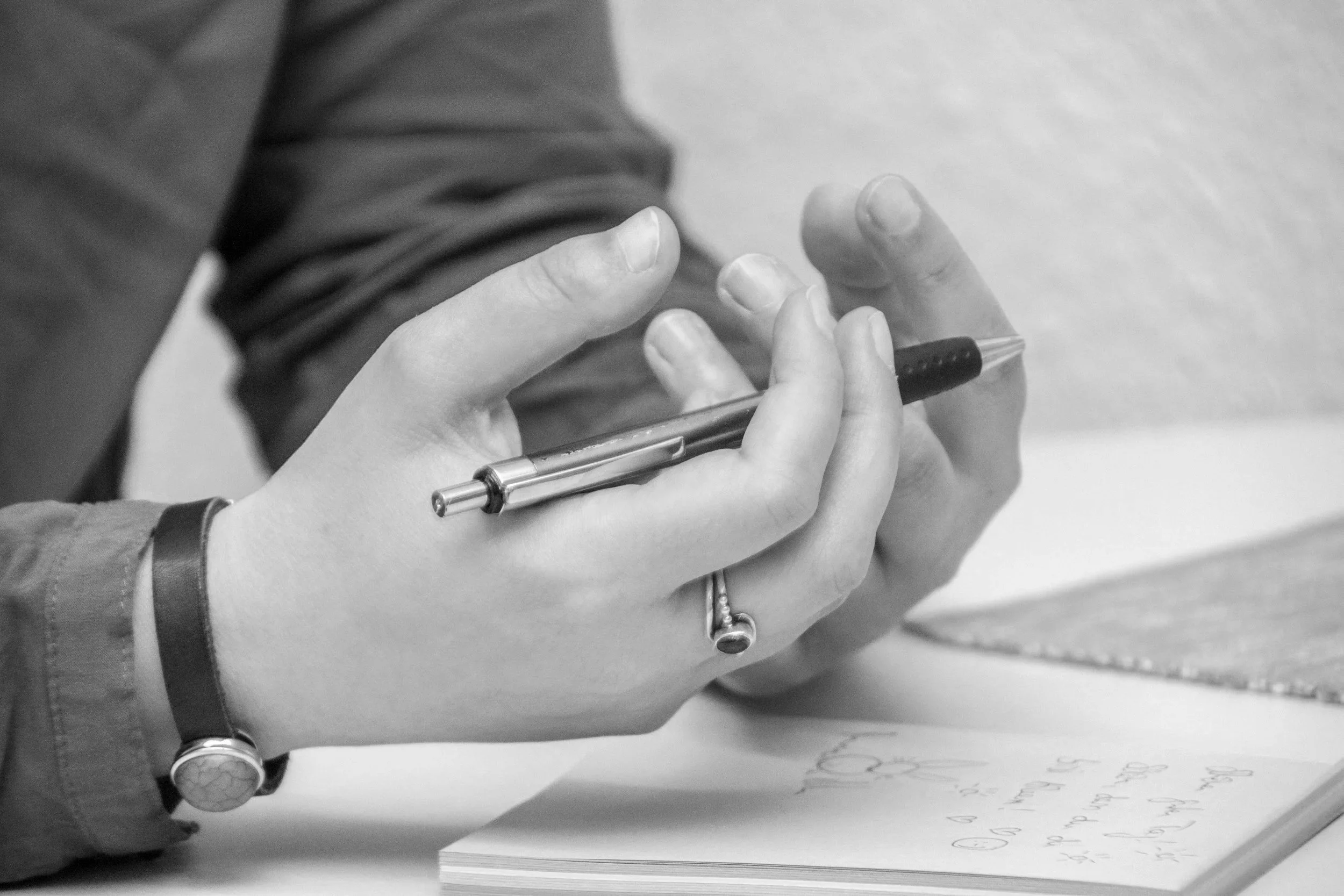 Close-up of a person's hand holding a pen and writing on a sheet of paper.