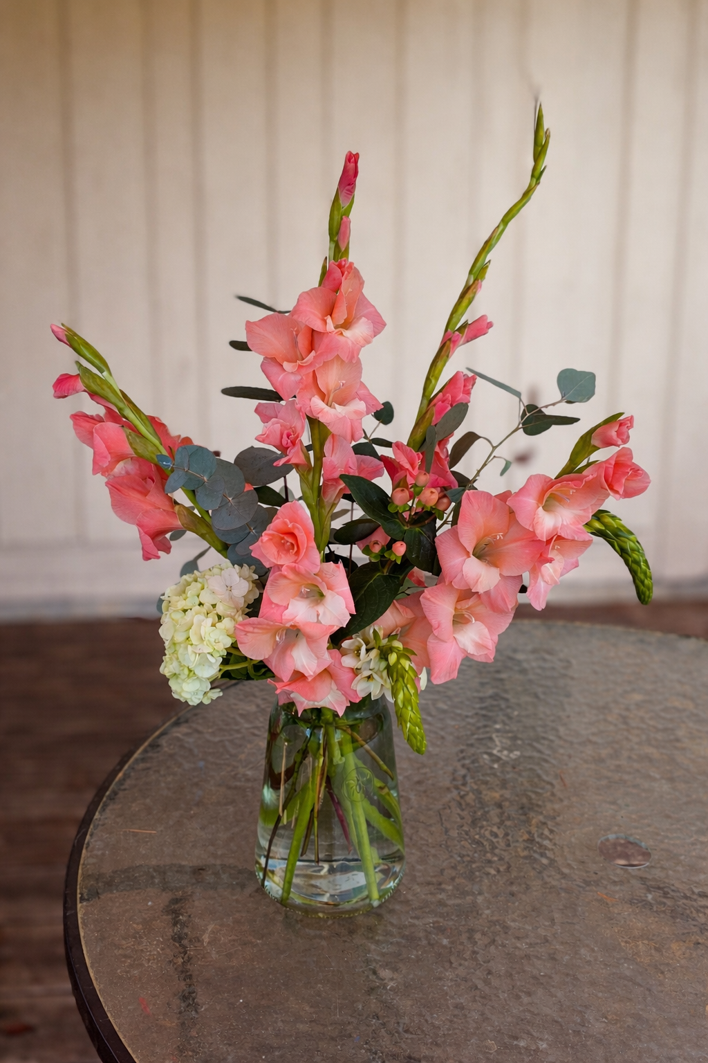 Coral-pink gladioli bouquet on table.png