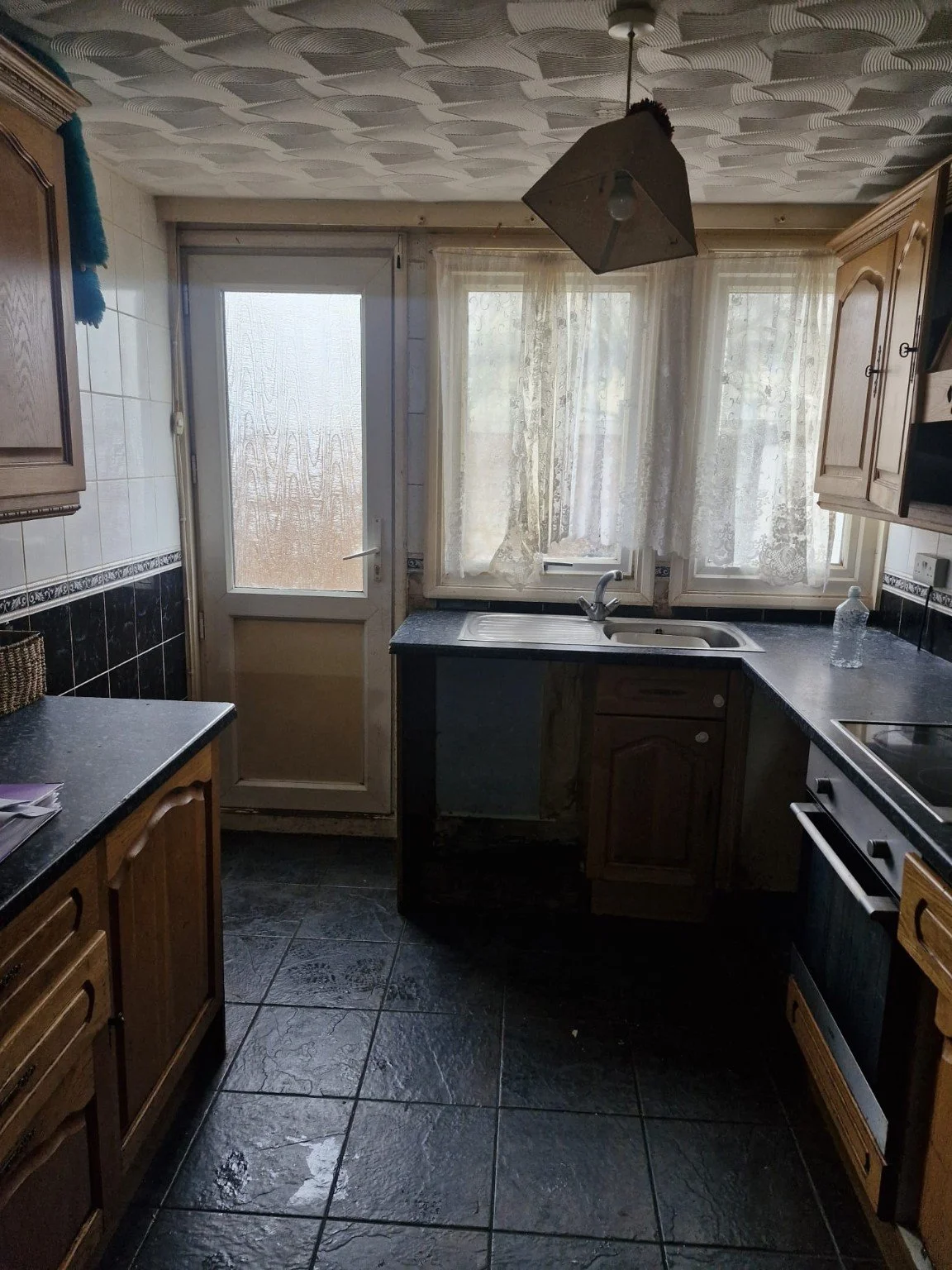 Gosport rental kitchen with wooden cabinets, dark worktops and tiled floor before refurbishment