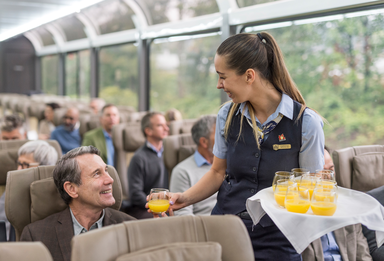 Flight attendant serving orange juice to a male passenger on a plane