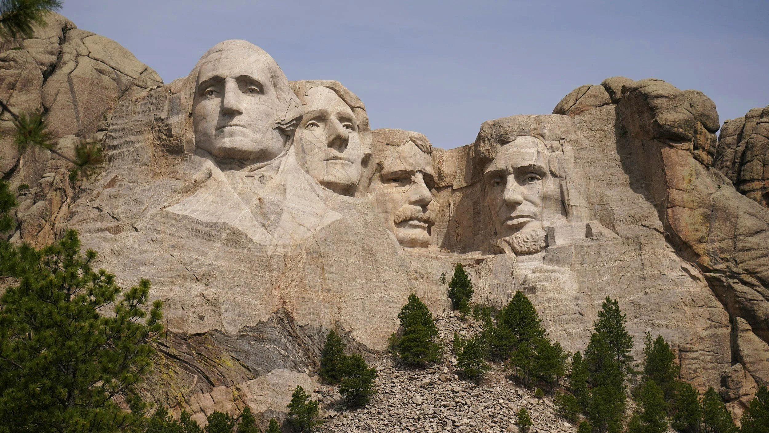 Close-up view of Mount Rushmore, featuring the carved faces of four U.S. presidents in the mountain, surrounded by trees and rocky terrain.
