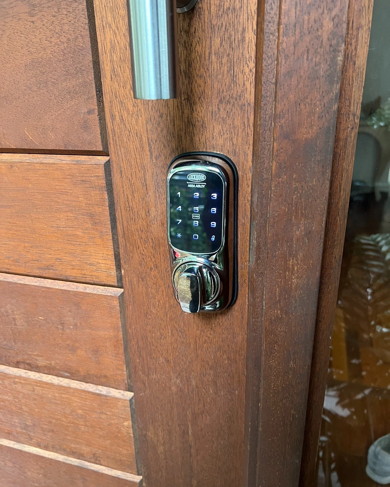 Digital smart lock keypad on a wooden door.