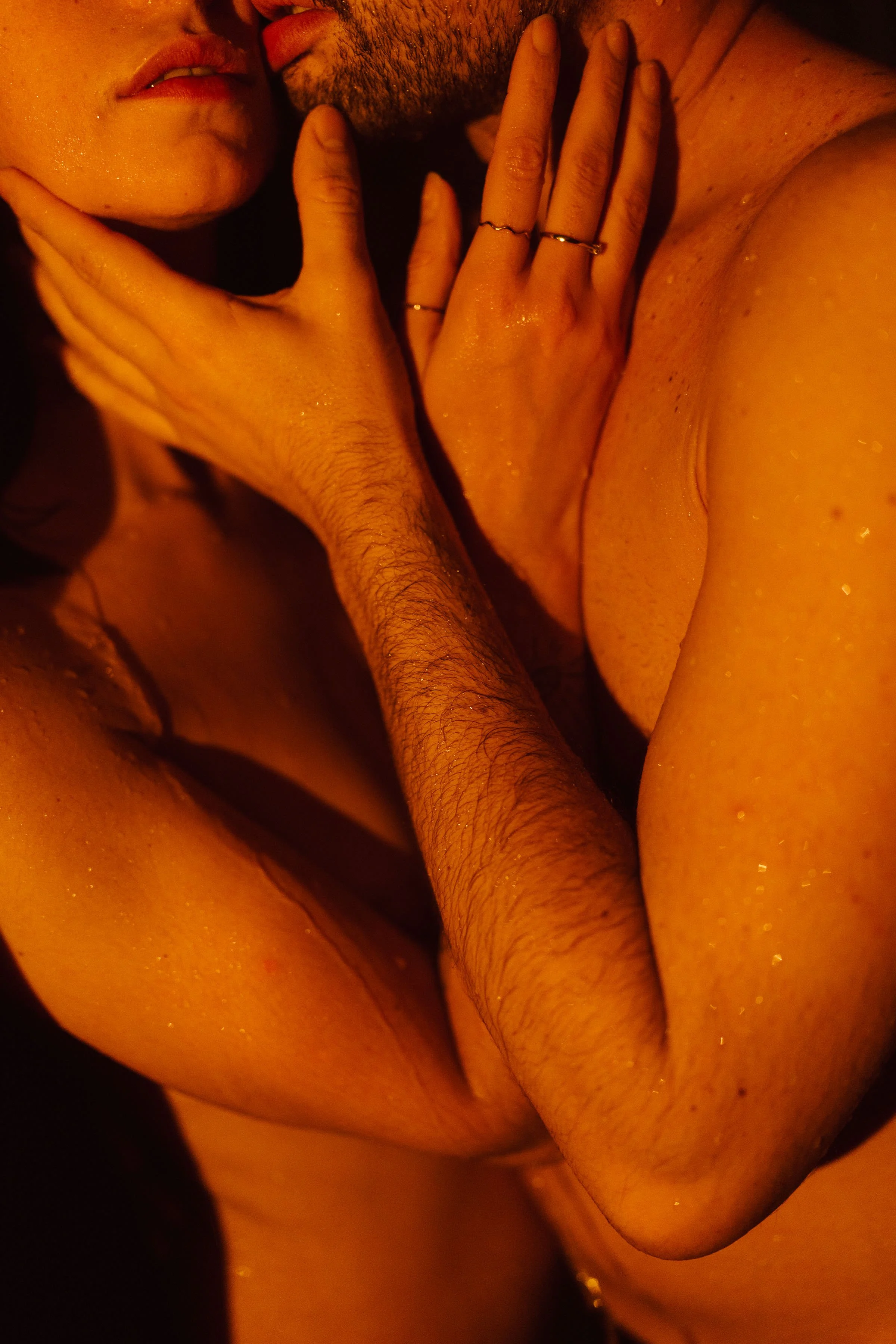 Portrait intime et artistique de couple en lumière chaude : une image sensorielle et éditoriale capturant la proximité, la peau et l’émotion dans une ambiance cinématographique signée Nonante Émotions.