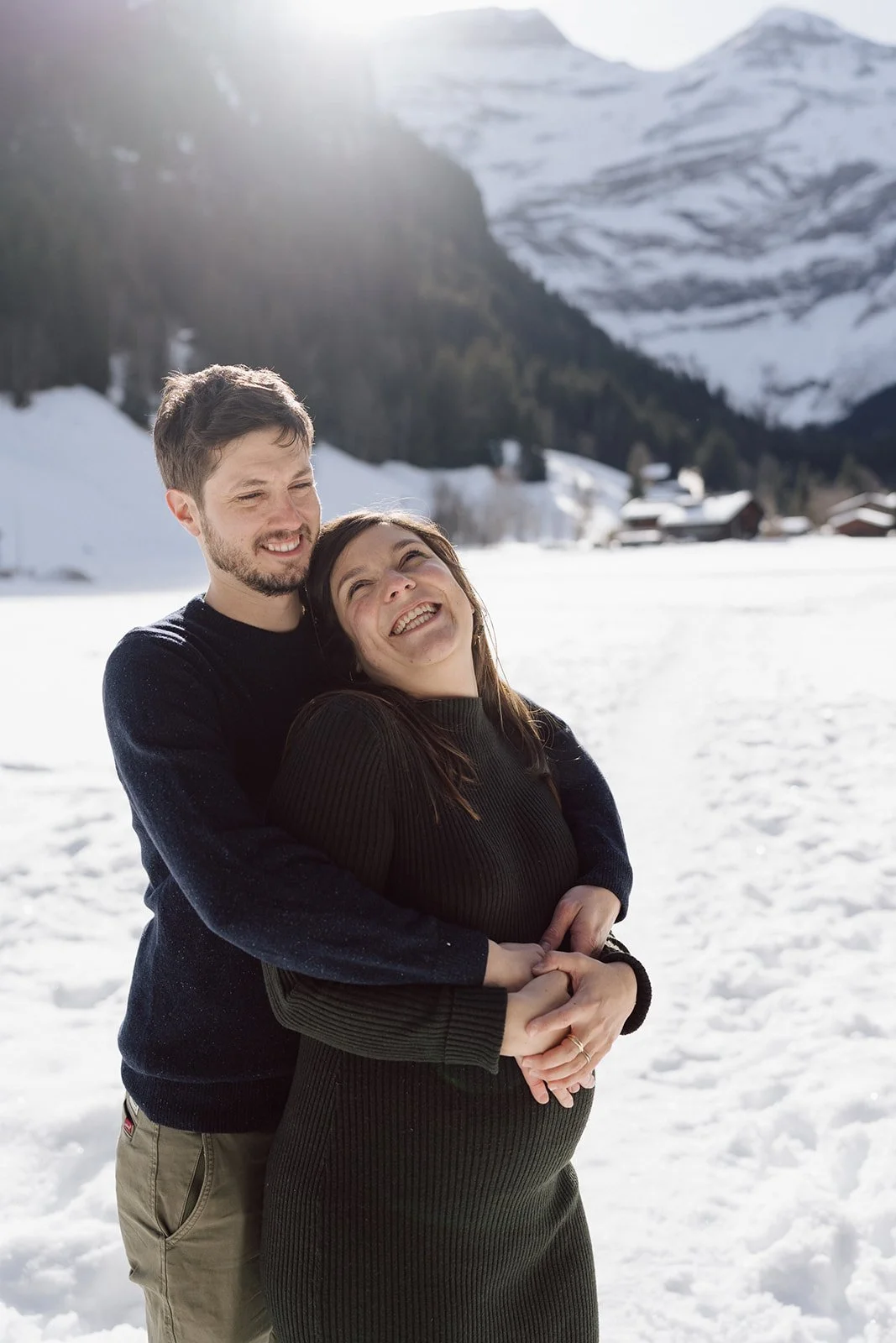 Séance photo grossesse en montagne enneigée : un couple partage un instant tendre et lumineux au cœur des Alpes, entre neige, soleil d’hiver et joie d’attendre leur bébé.