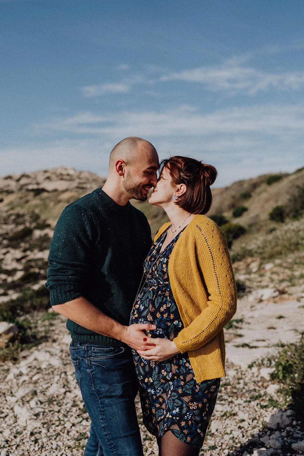 Séance grossesse à Marseille: un couple partage un moment tendre et complice dans un paysage naturel, célébrant l’attente de leur bébé.