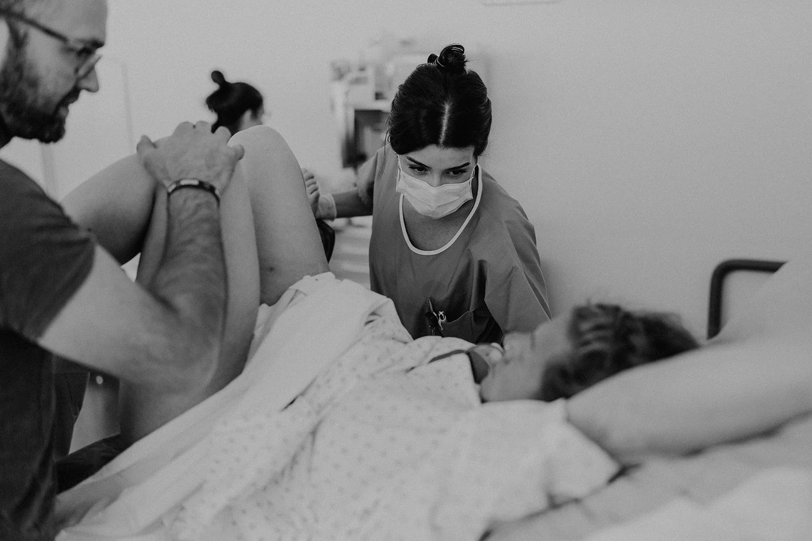 La force d’une équipe bienveillante en salle de naissance : sage-femme, partenaire et maman unis dans l’intensité de l’accouchement, capturés en reportage en Suisse romande.