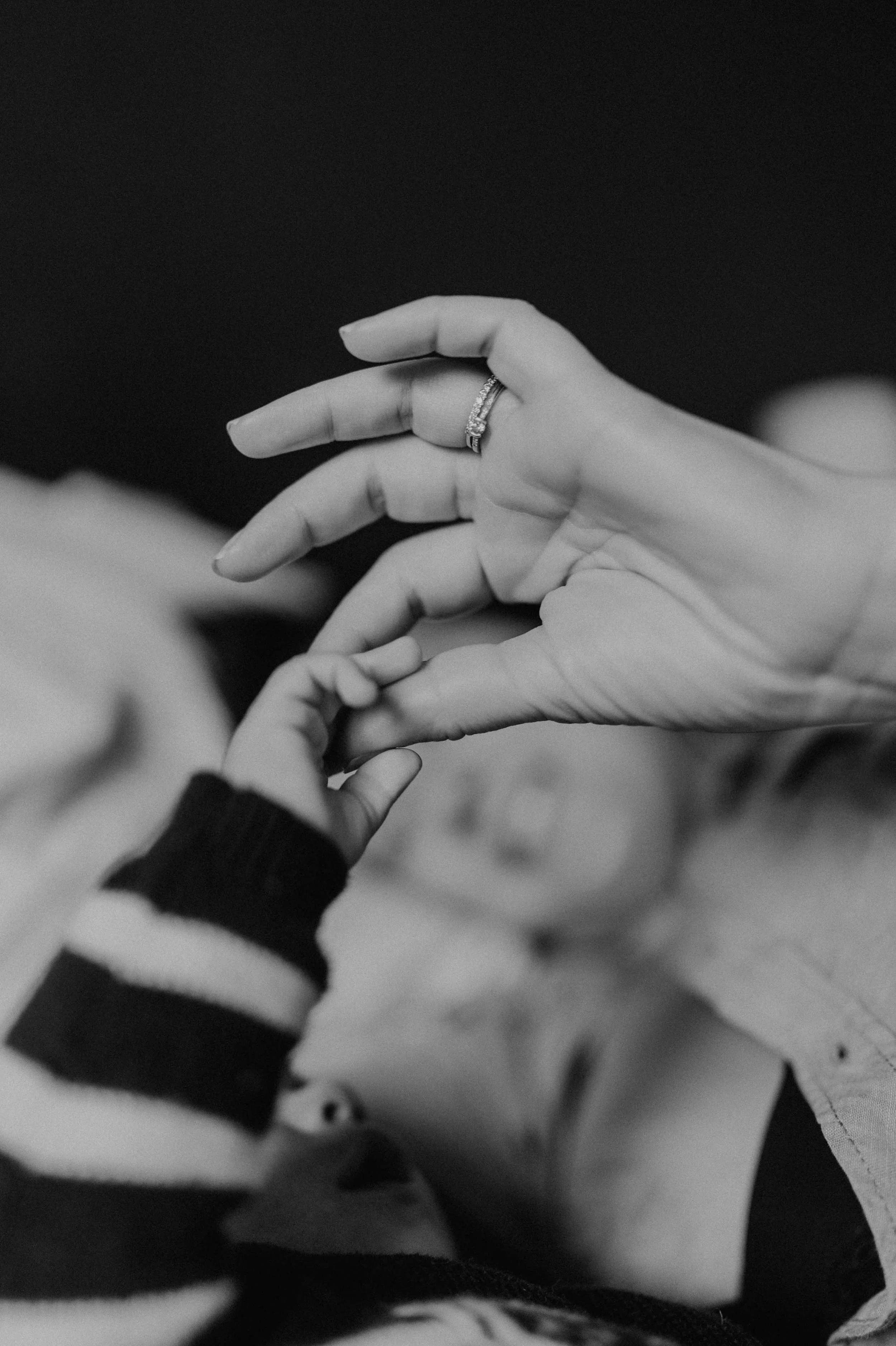 Main de bébé tenant le doigt de sa maman lors d’une séance maternité en Suisse romande