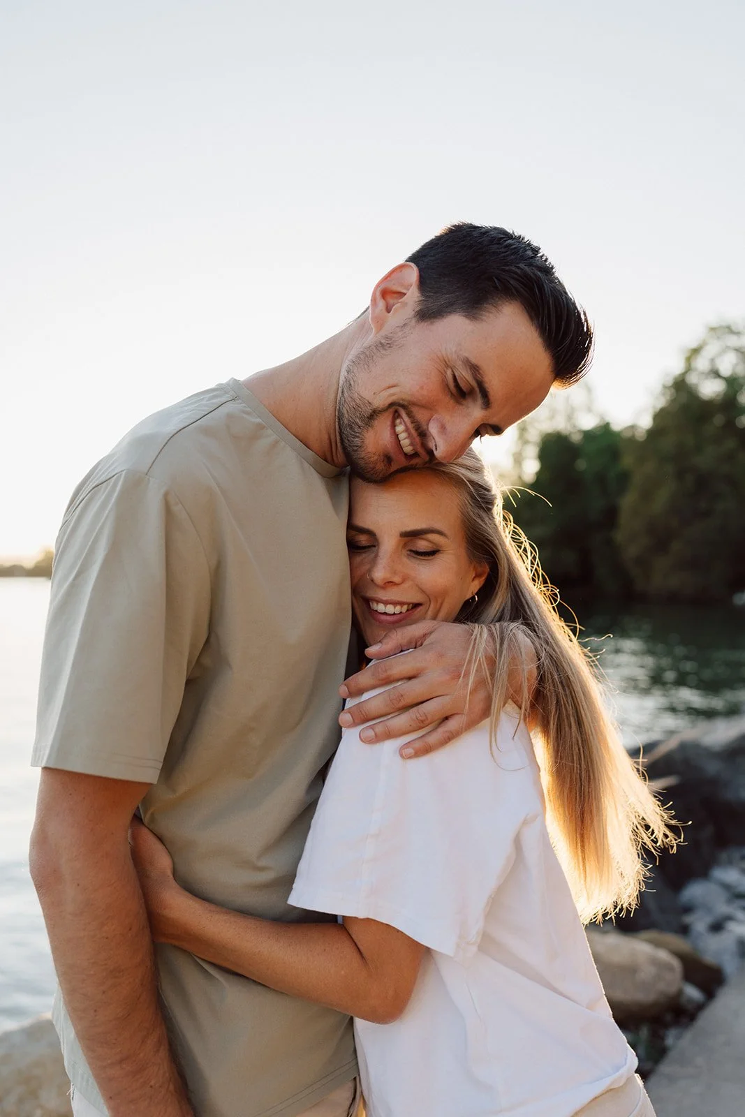 Portrait de couple au bord du lac au coucher du soleil : une étreinte tendre et lumineuse capturée dans un instant d’amour, de douceur et de connexion authentique.