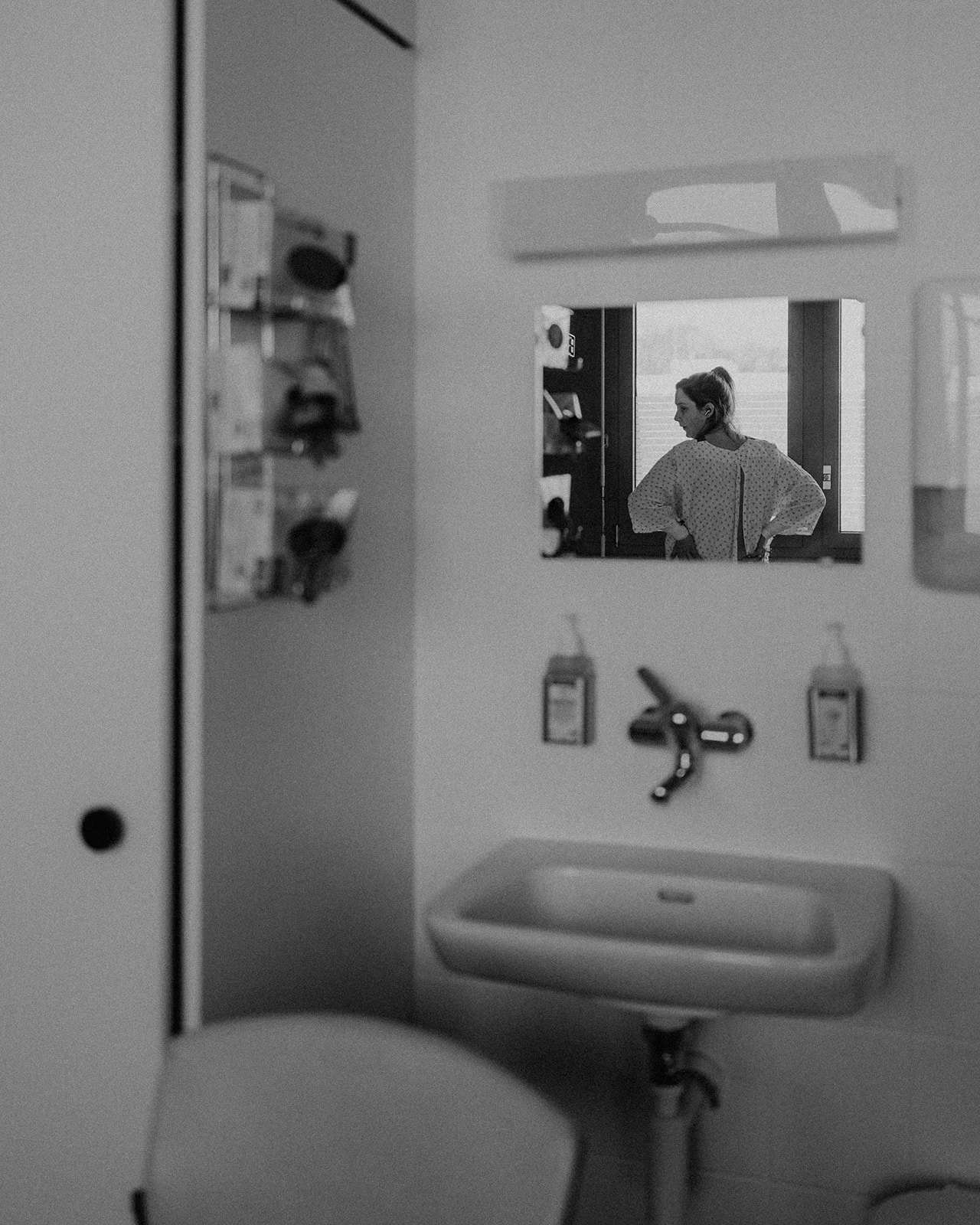 Future maman en travail observée dans le reflet d’un miroir en salle de naissance pendant un reportage d’accouchement en Suisse romande