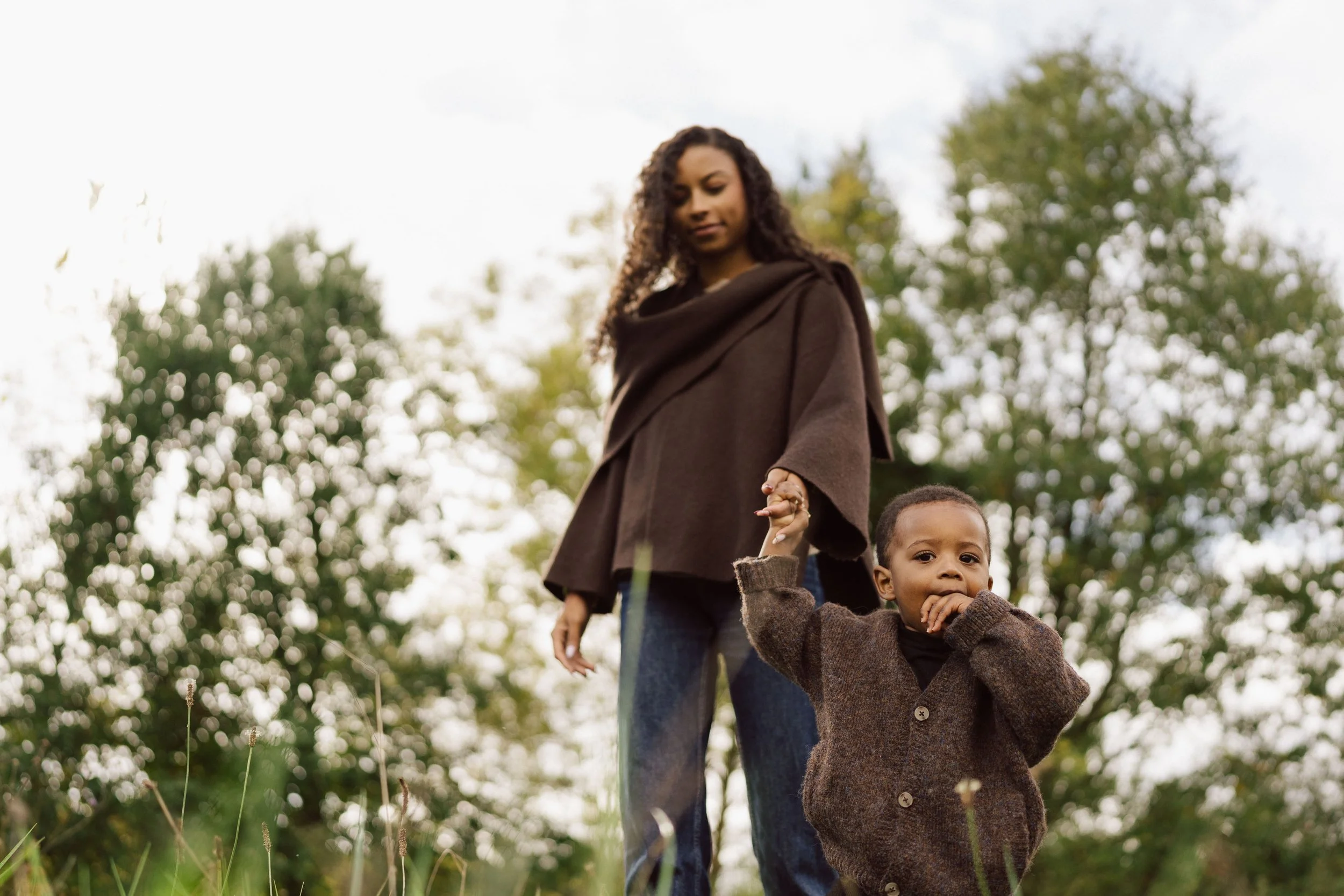 Mère et enfant marchant main dans la main en pleine nature, capturés dans une scène douce et spontanée lors d’une séance famille lifestyle en extérieur par Nonante Émotions.