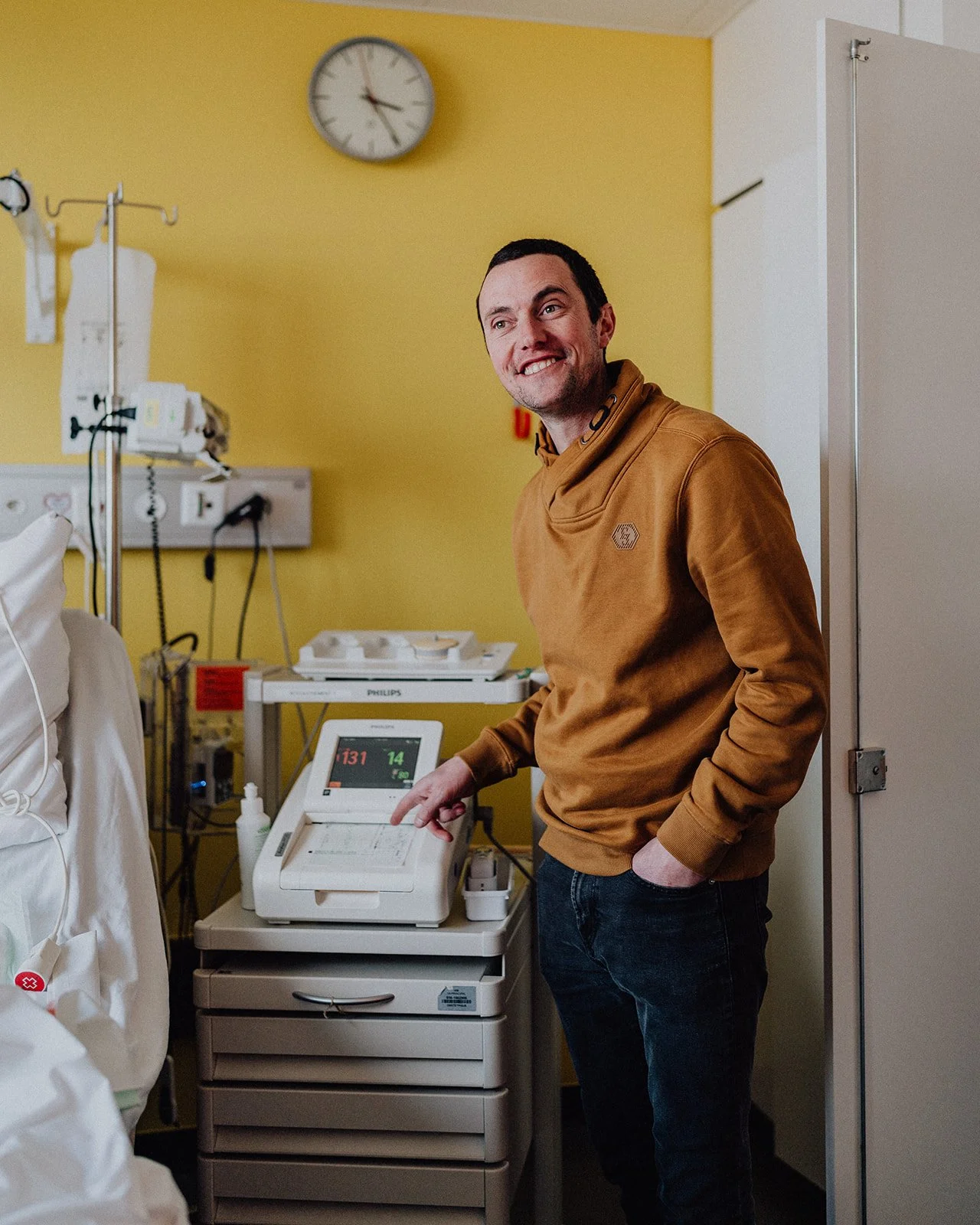 Futur papa observant le monitoring en salle de naissance pendant un reportage d’accouchement en Suisse romande