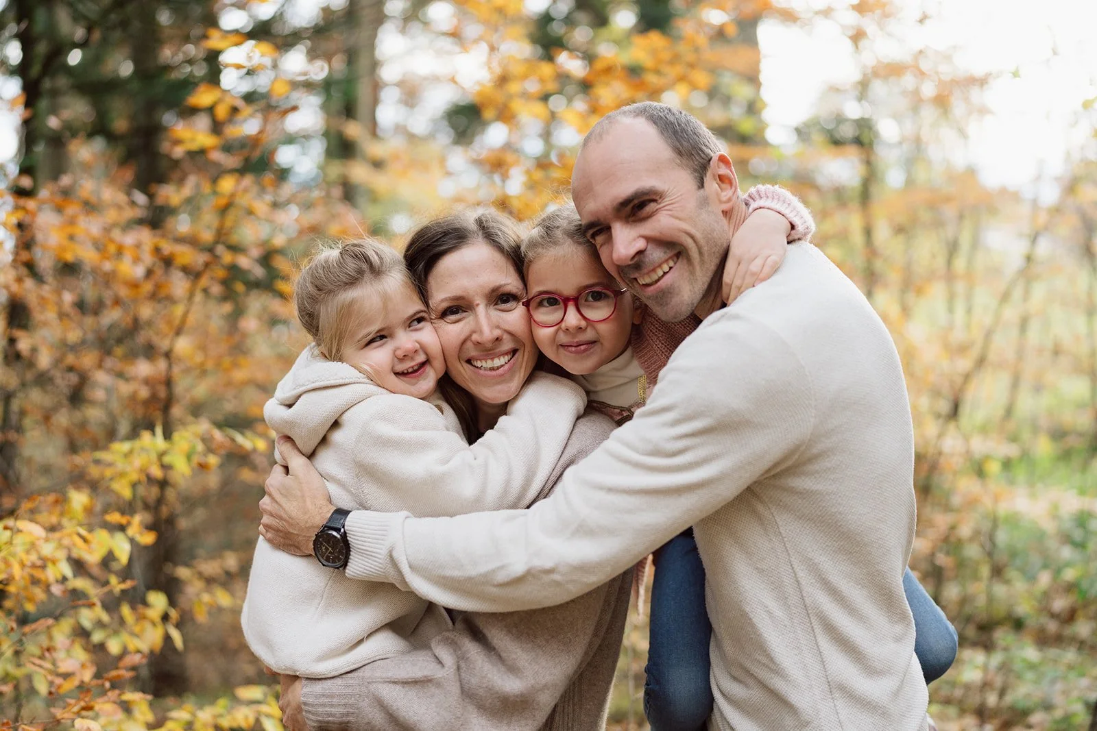 Portrait de famille en forêt automnale en Suisse : une séance photo lifestyle naturelle et chaleureuse, immortalisant tendresse, sourires et complicité entre parents et enfants par Nonante Émotions.