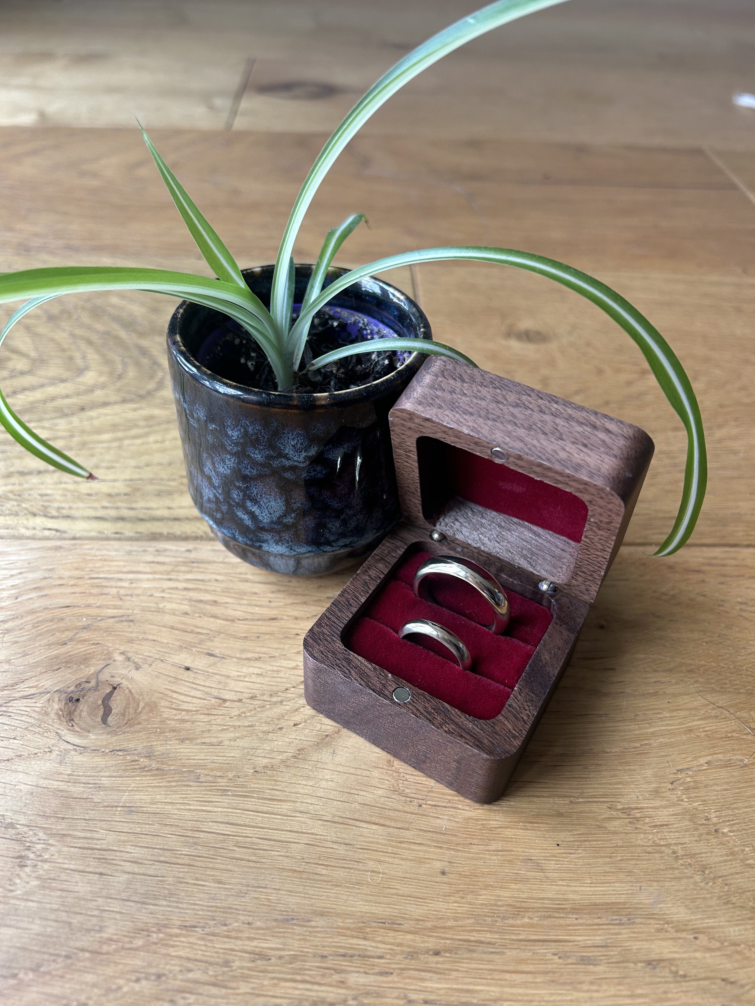 A wooden jewellery box holding two 9ct gold wedding rings 