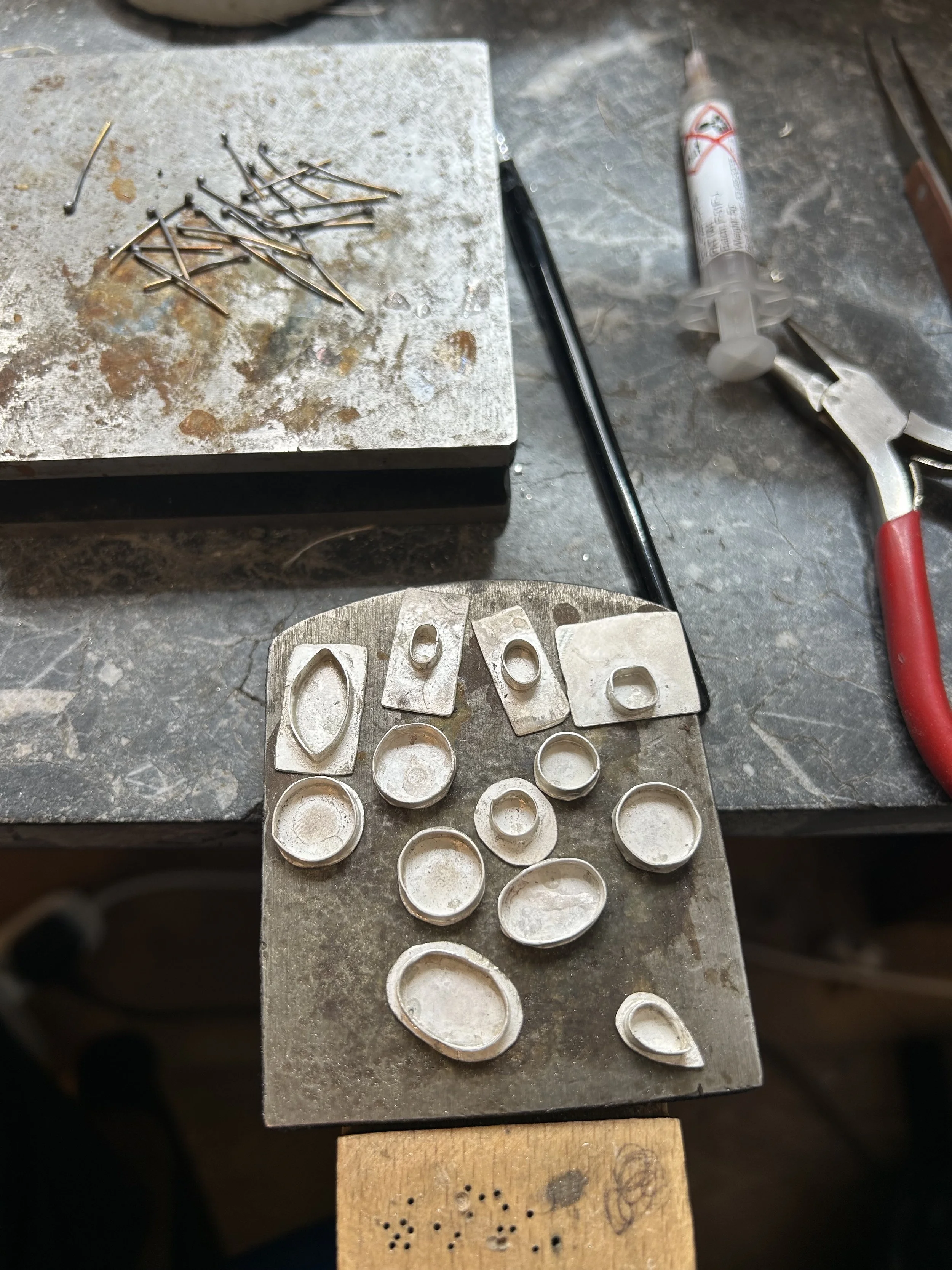 Sheet of metal with various cut-out shapes, on a workbench with a wooden board underneath.