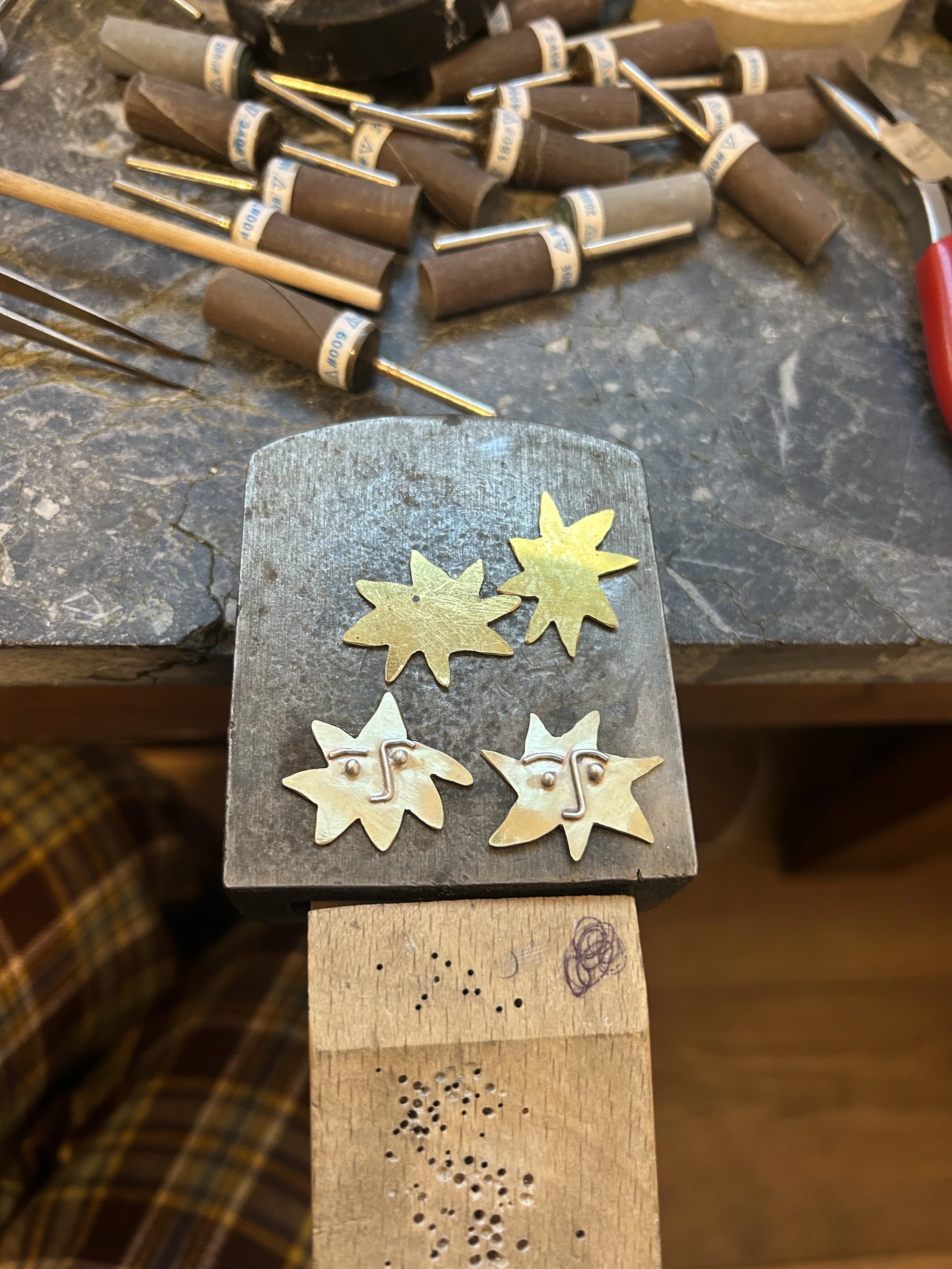 A workbench, with brass star shapes from unfinished jewellery pieces