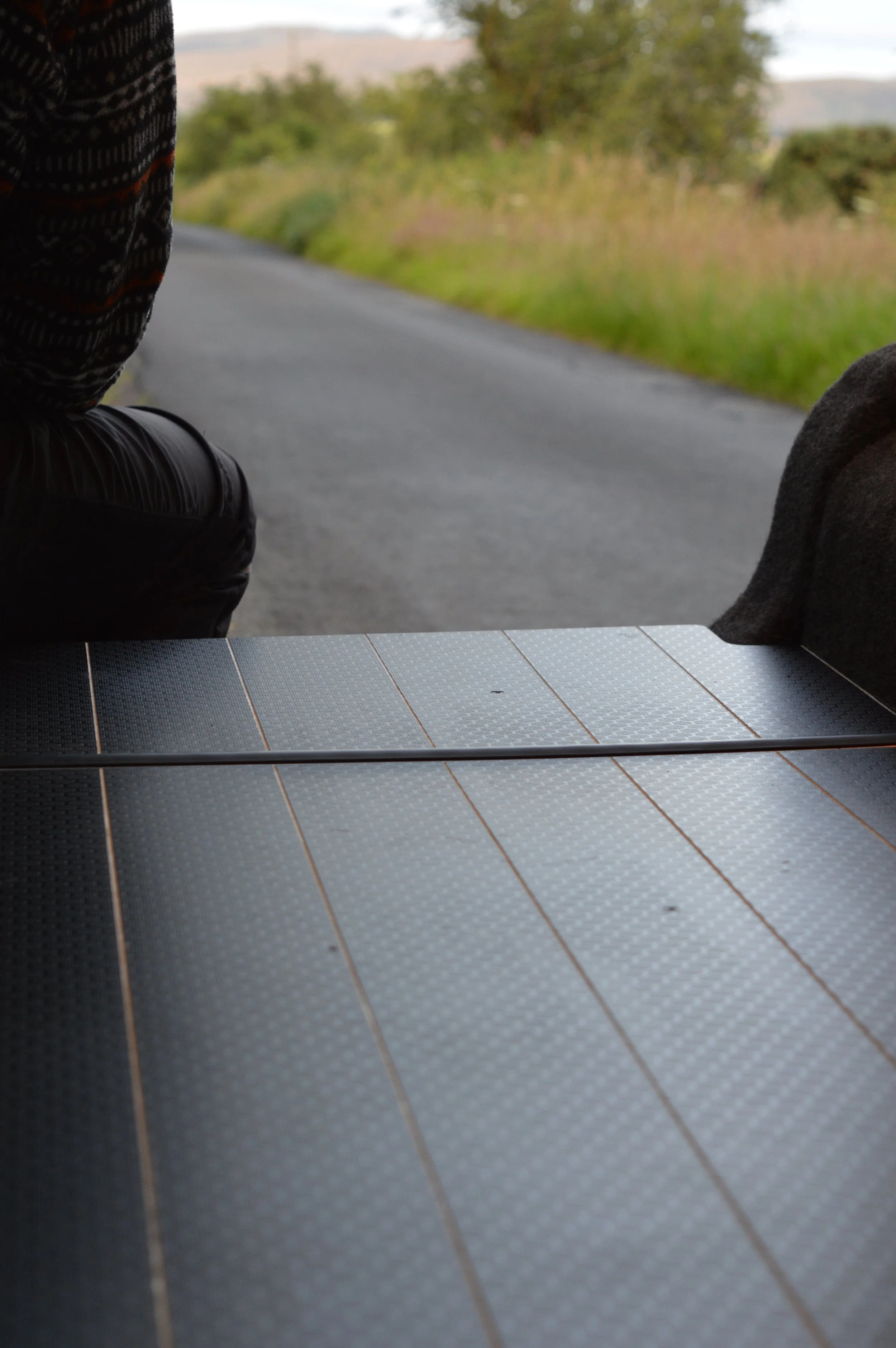Person sitting at the back of the Ohm Campers Campervan showing bespoke floor.