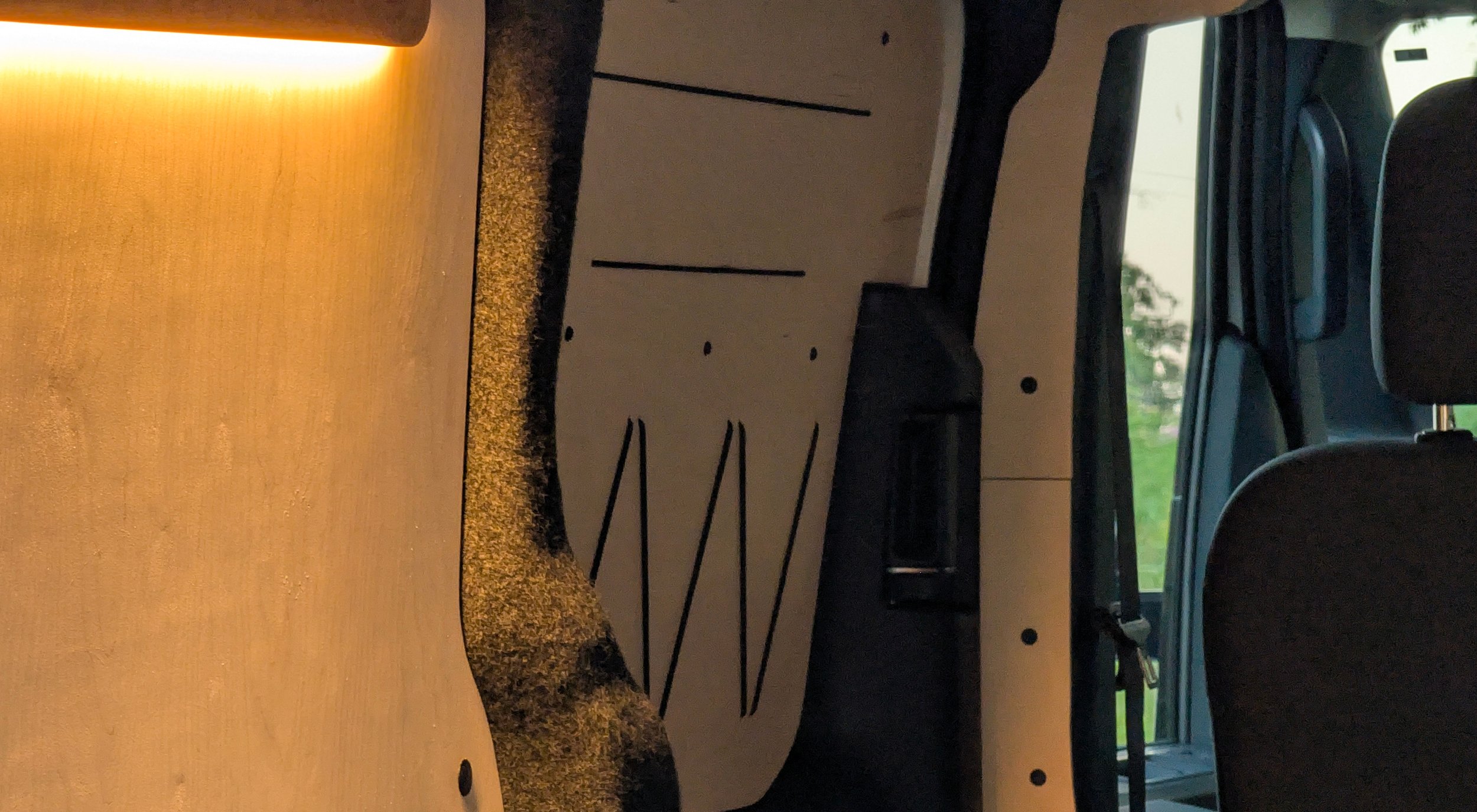 Ohm Campers birch plywood campervan interior walls and door with LED lighting and bungee attachments.