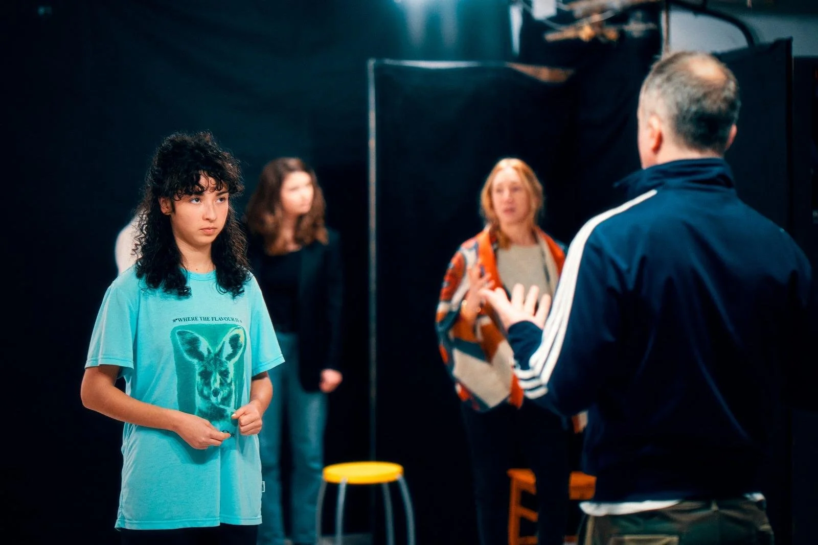 Un groupe de personnes en discussion ou en répétition dans un studio noir.