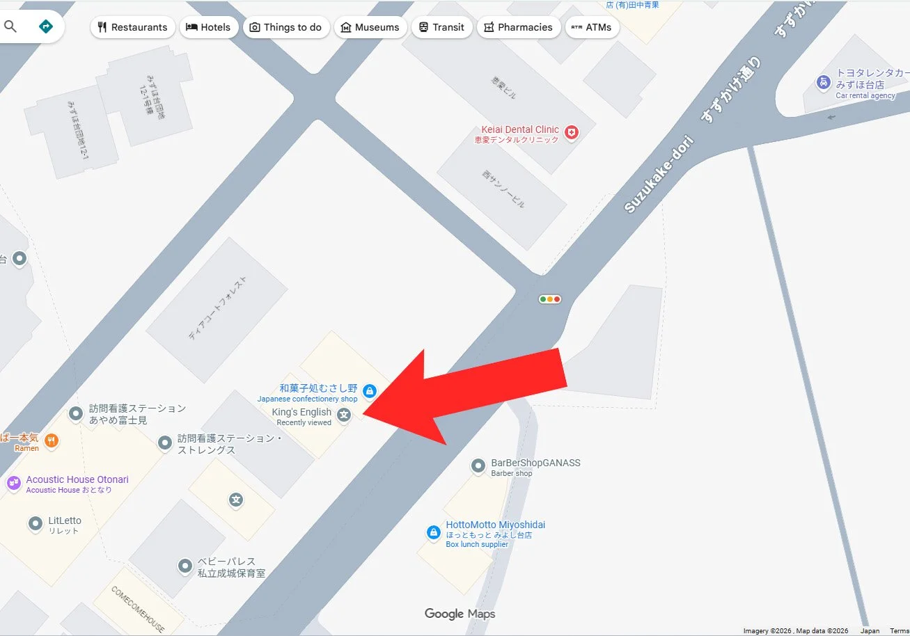 みずほ台の鈴木通り周辺を示す地図で、特定の建物を拡大した赤い矢印が指し示し、近くに和菓子店・英会話スクール King’s English・理容室・弁当店が表示された案内図