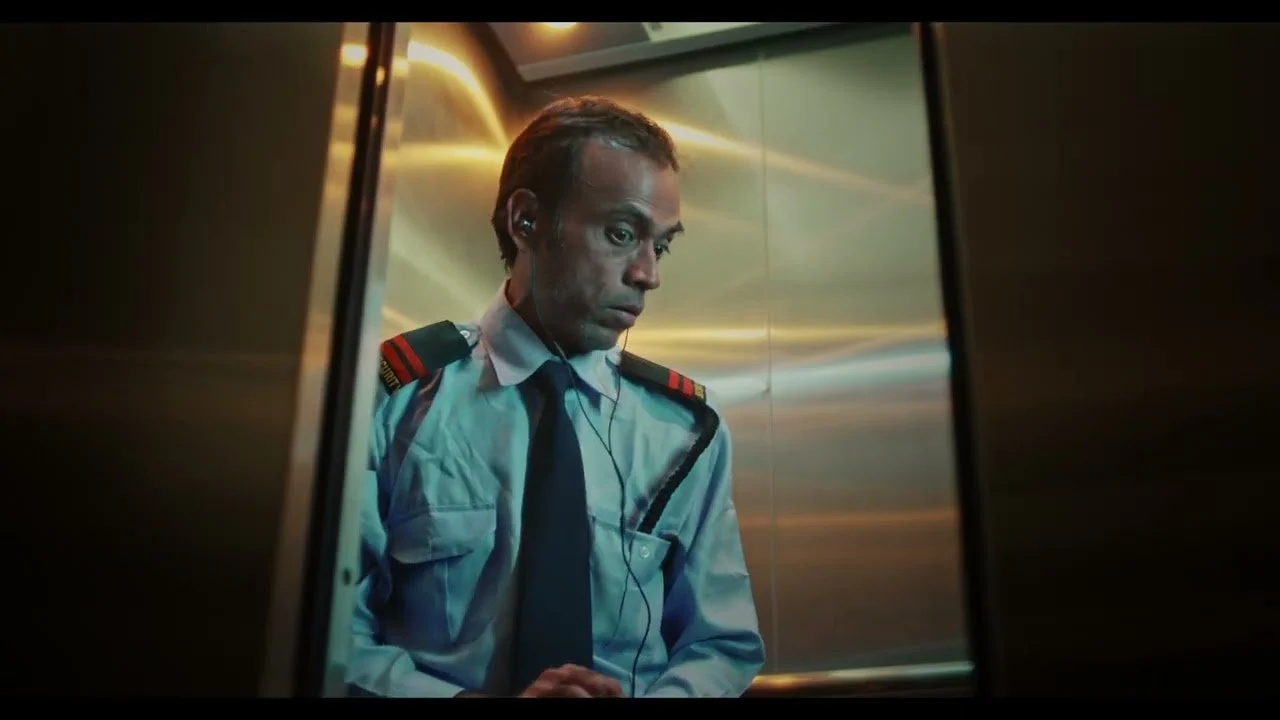 A man dressed as a flight attendant looking down inside an elevator