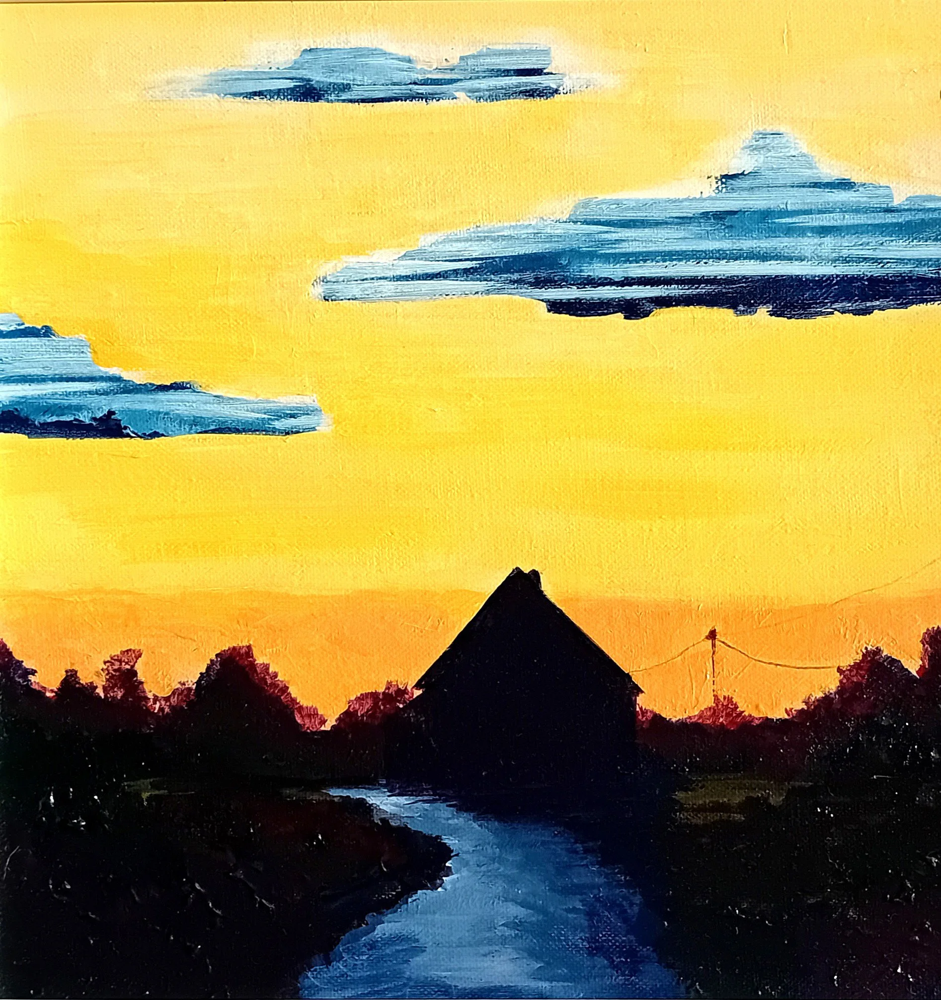 Silhouette of a house by a stream during sunset with a sky painted yellow, orange, and blue clouds.