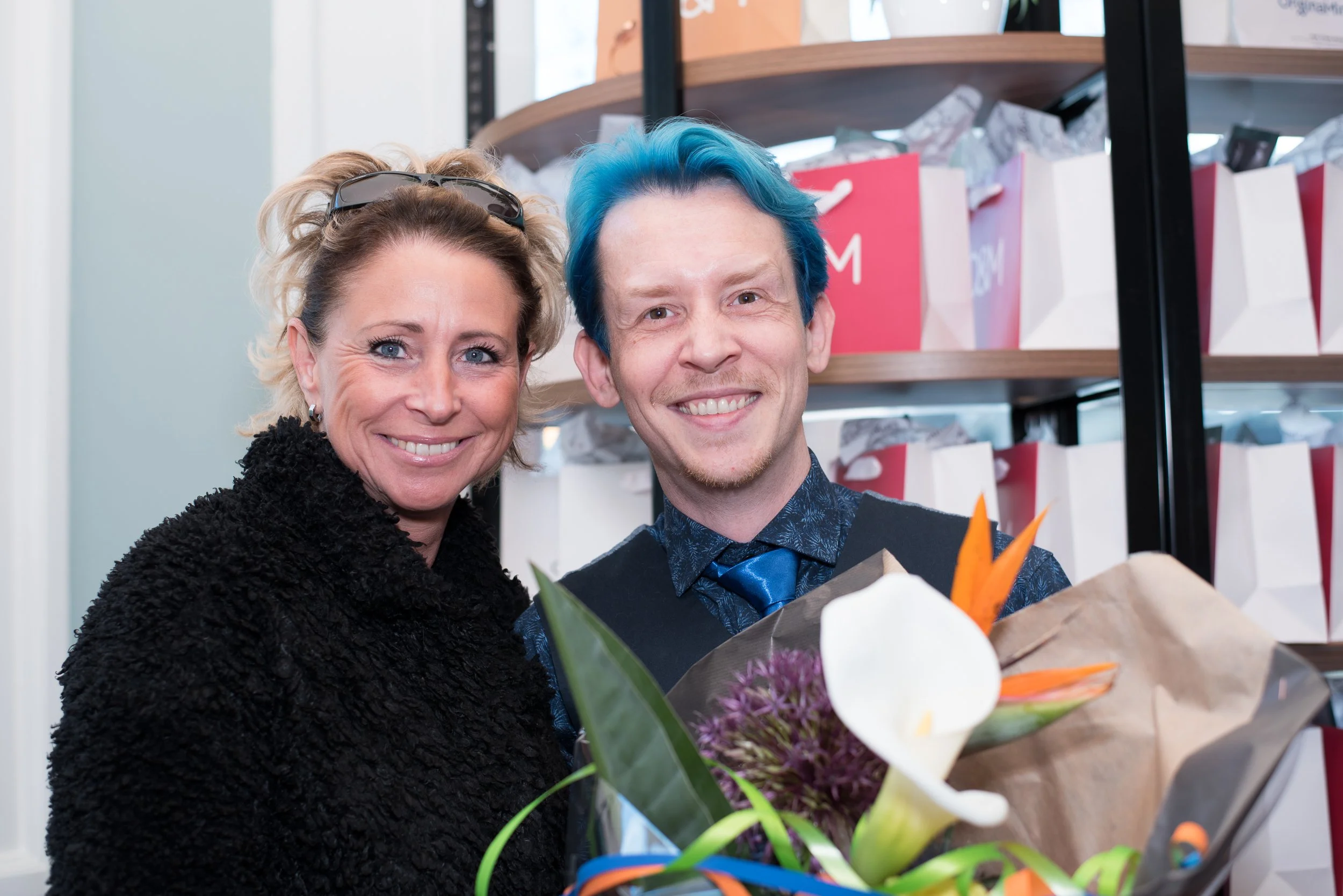 Vrolijk sfeerbeeld van een man en vrouw met een groot boeket bloemen tijdens een feest.
