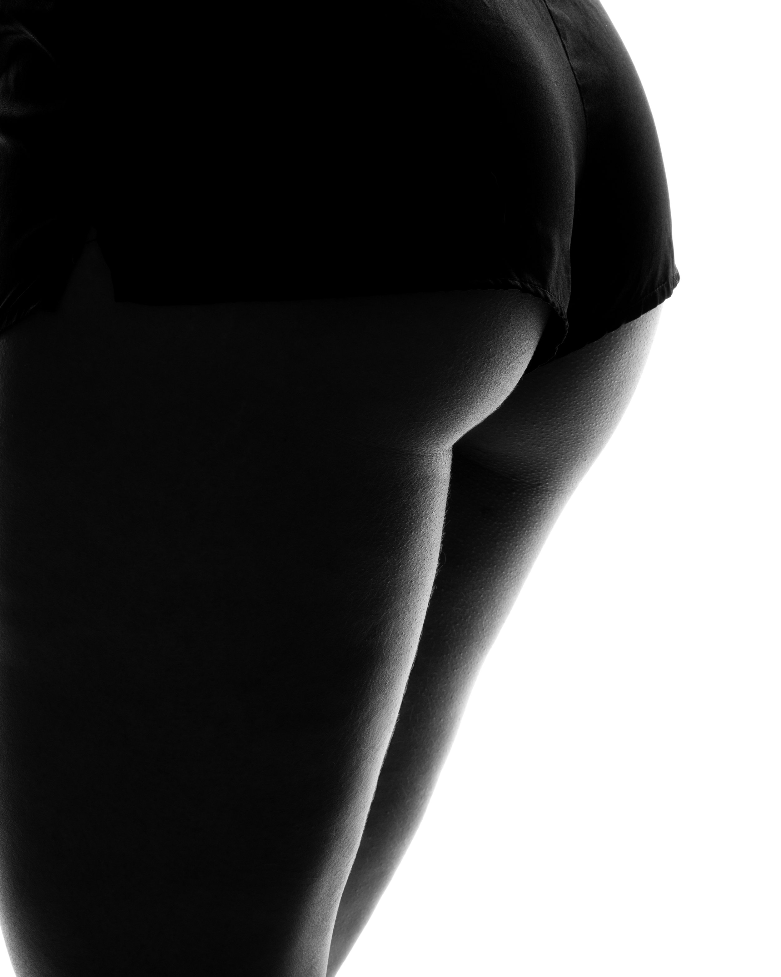 Artistieke zwart-wit silhouetfotografie van de contouren van een vrouwelijk lichaam in lingerie.