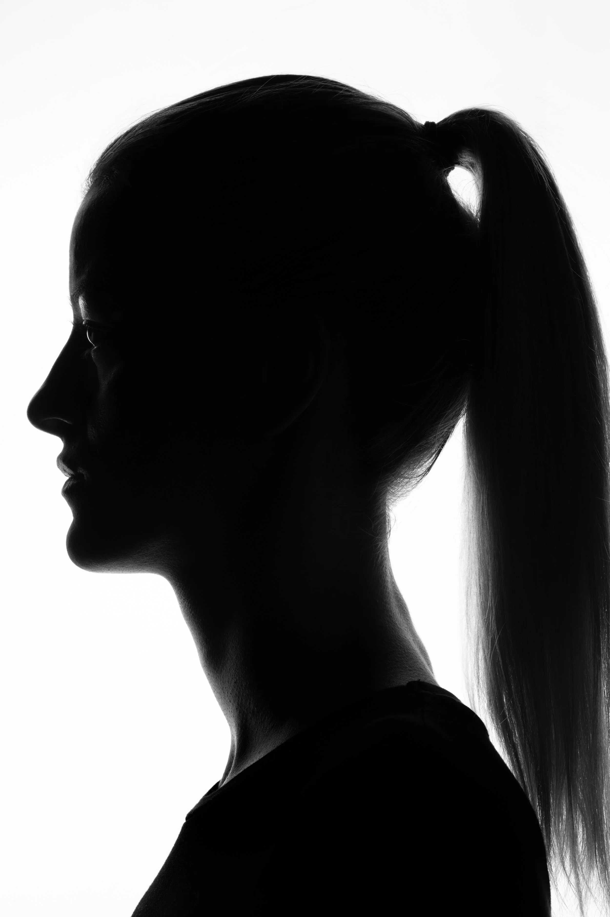 Artistiek zwart-wit silhouet van het zijprofiel van een vrouw met een paardenstaart.