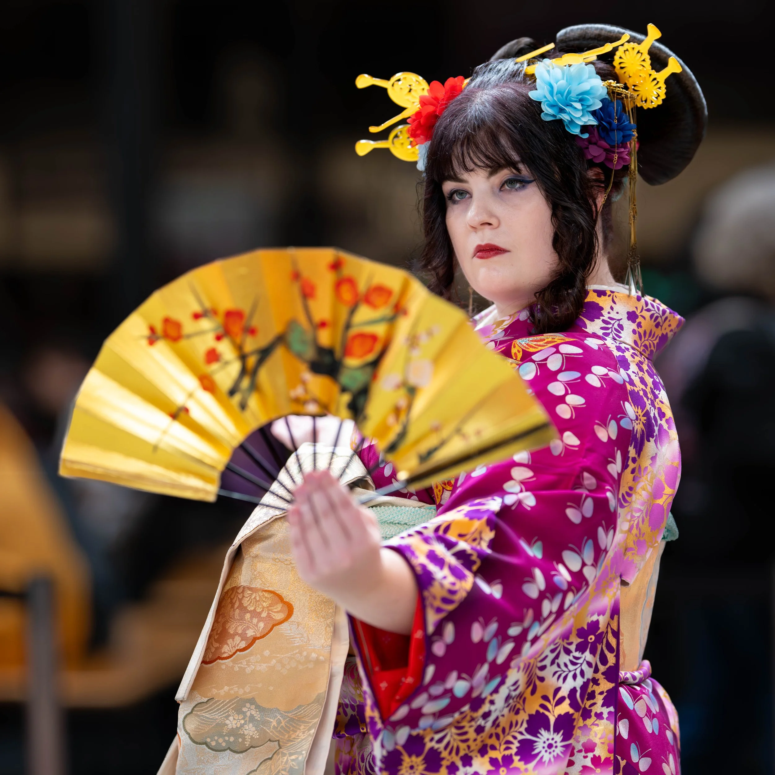 Prachtig cosplay portret van een vrouw in een paarse kimono die poseert met een gouden waaier. Geisha.