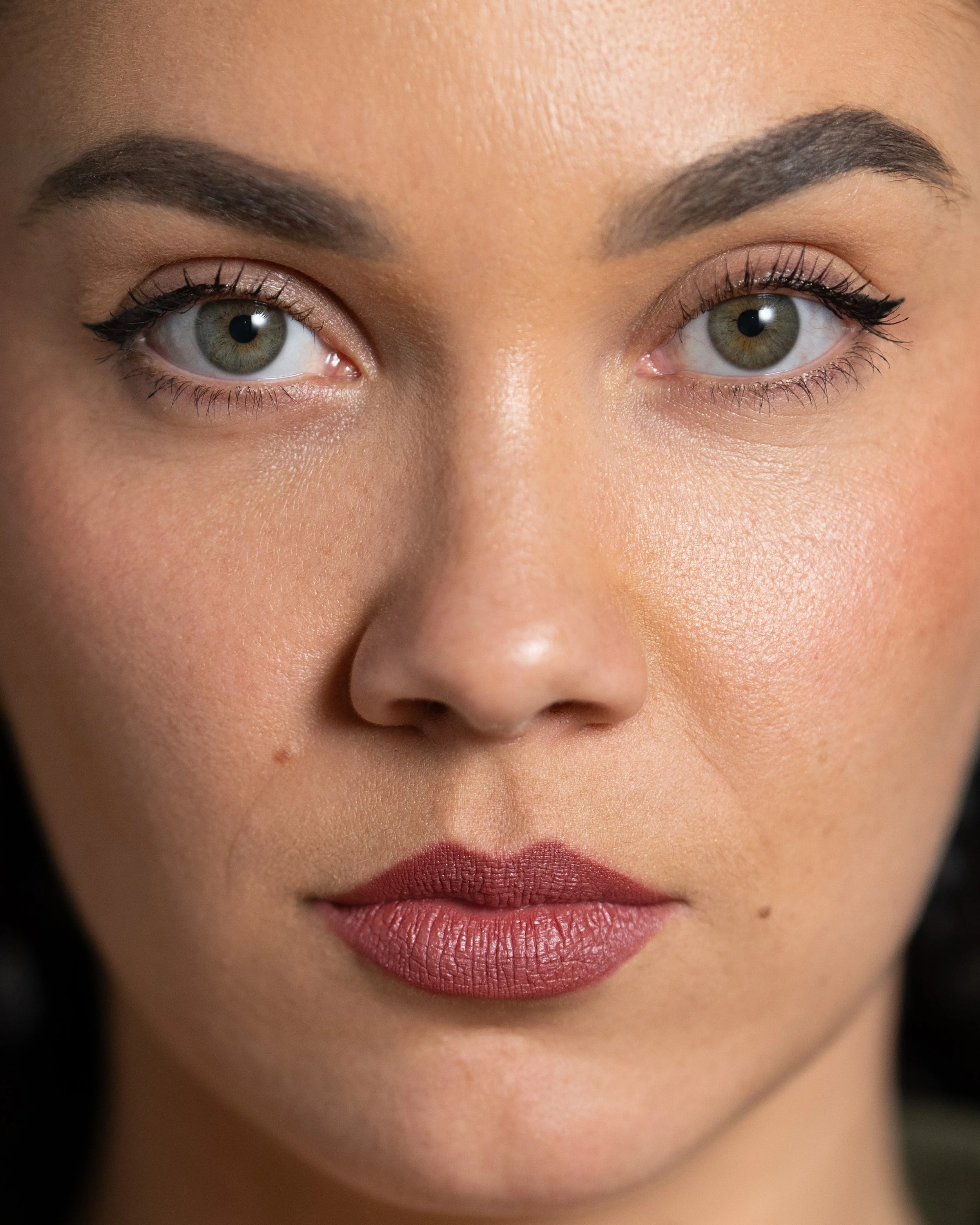 Extreme close-up van een vrouwelijk gezicht met de focus op de ogen en lippenstift.