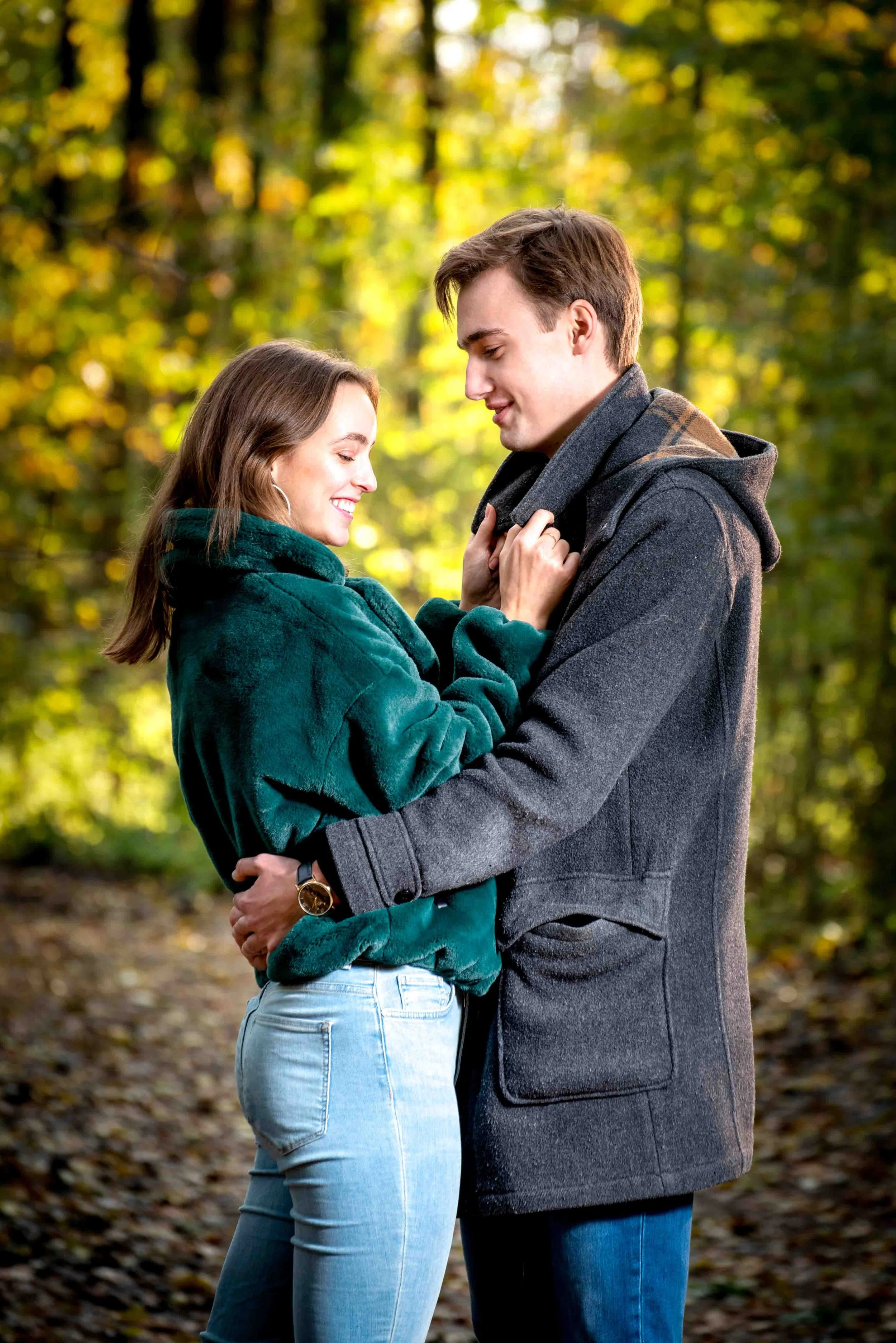 Spontane lifestyle fotografie van een verliefd koppel dat elkaar omhelst in een herfstbos.