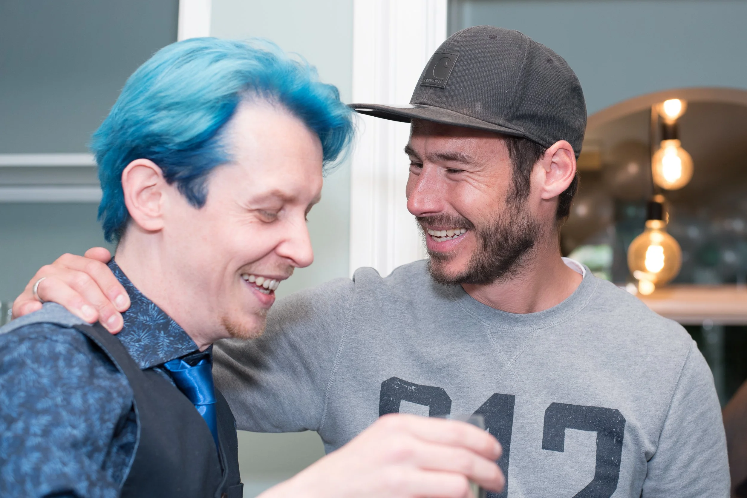 Spontane eventfotografie van twee lachende mannen in gesprek tijdens een gezellig evenement.