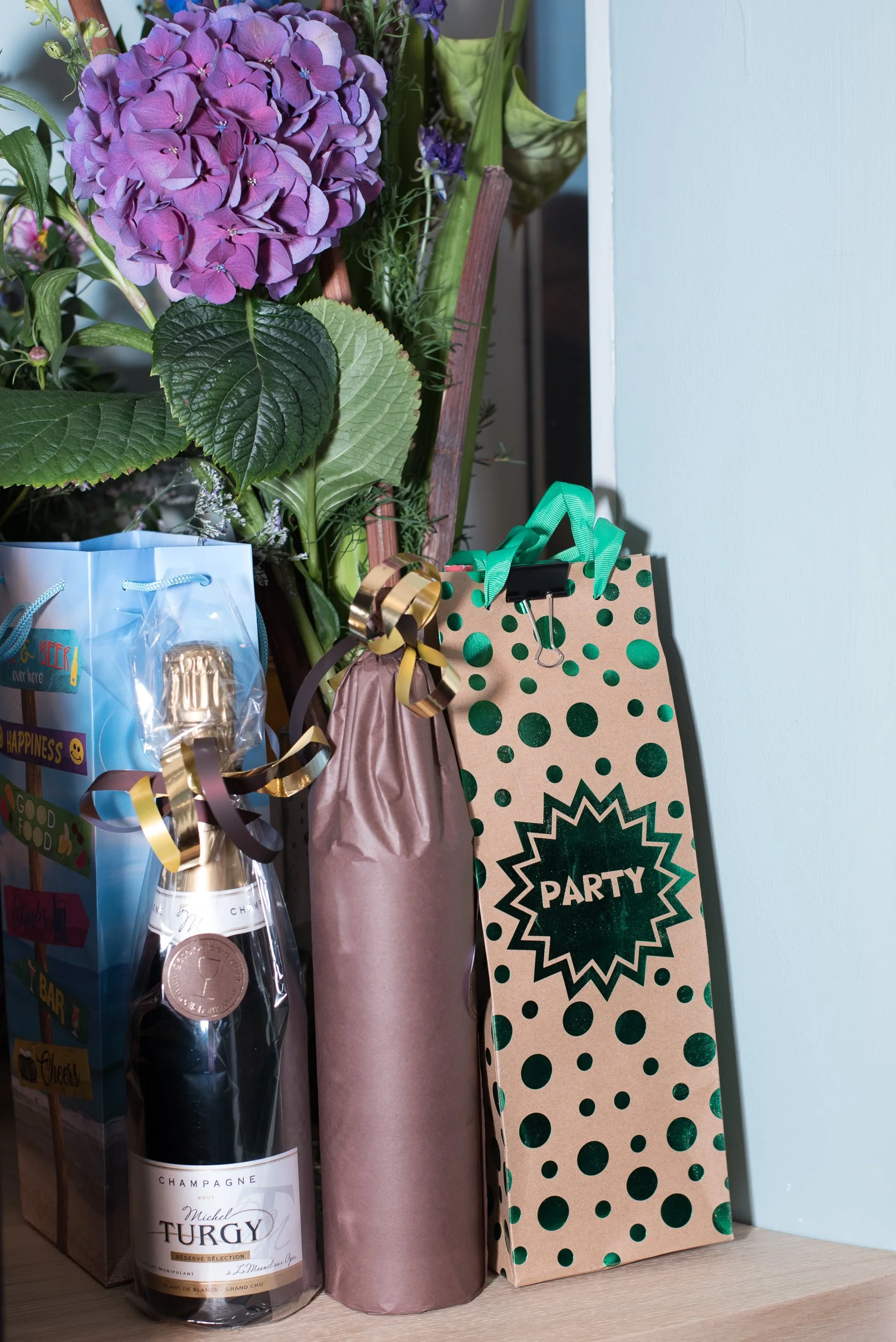 Detailopname van feestelijke cadeautassen en een fles champagne op een evenementenlocatie.