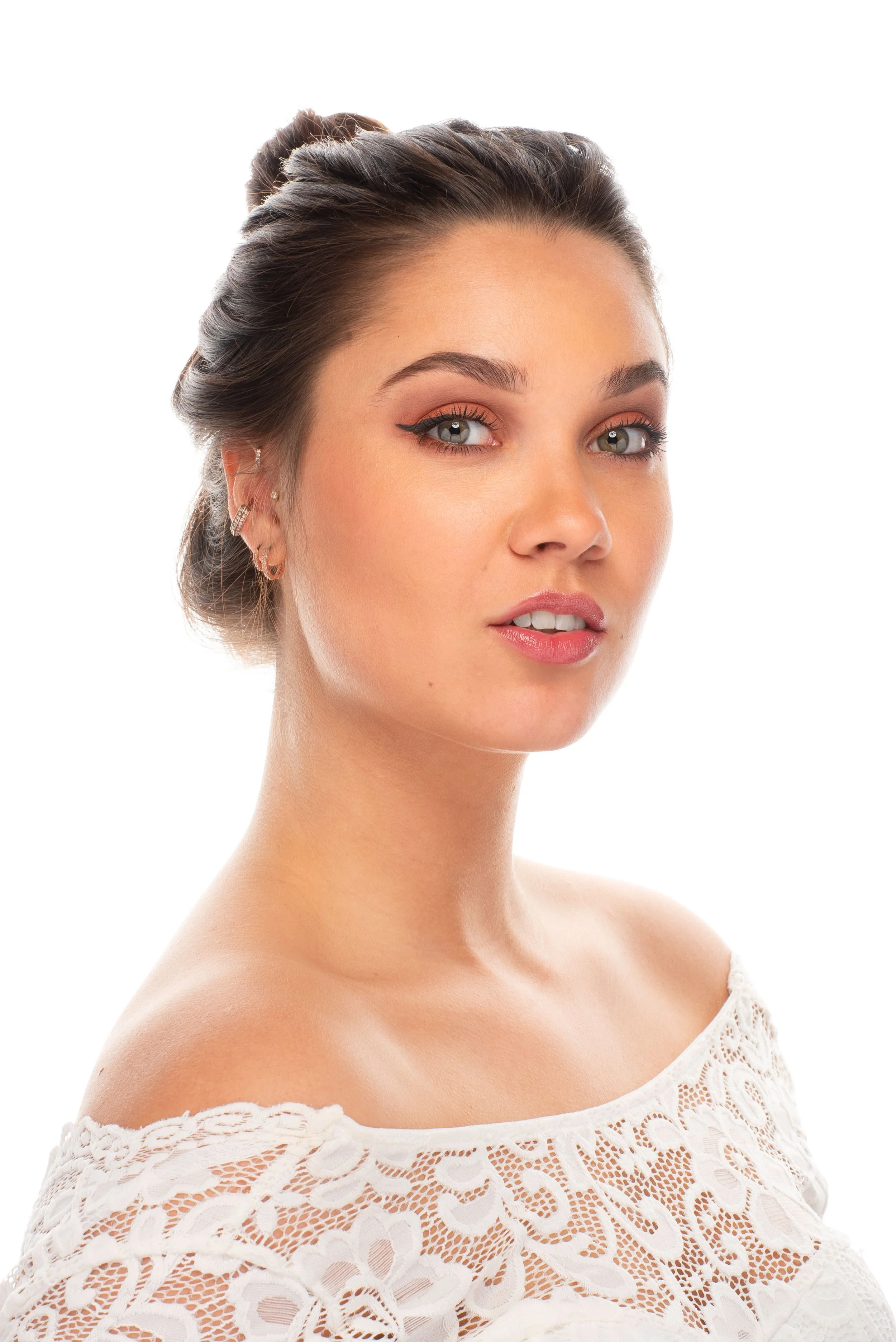 High-key portret van een vrouw met opgestoken haar en een kanten top tegen een witte achtergrond.