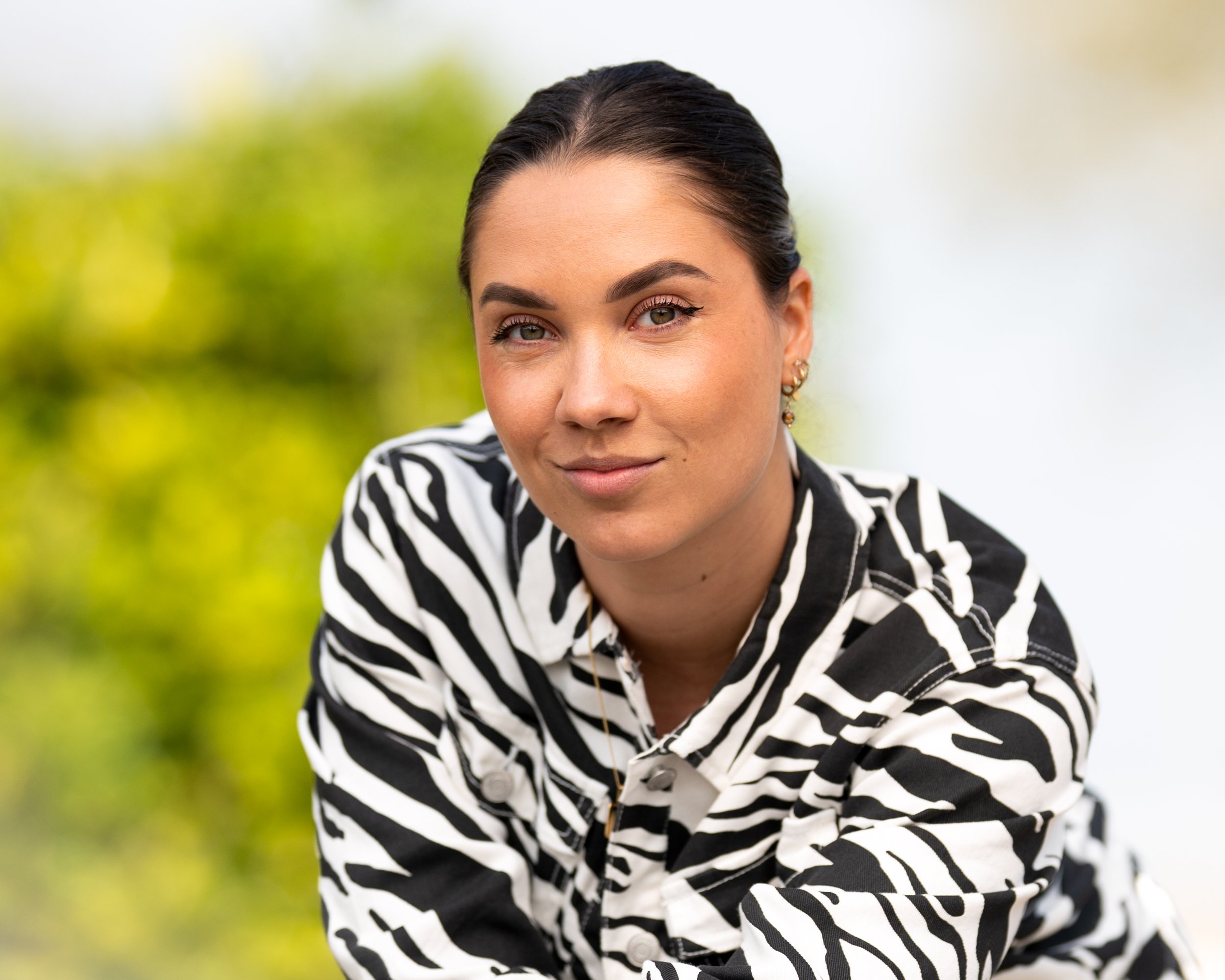 Natuurlijk buitenportret van een jonge vrouw in een zwart-witte zebraprint jas.