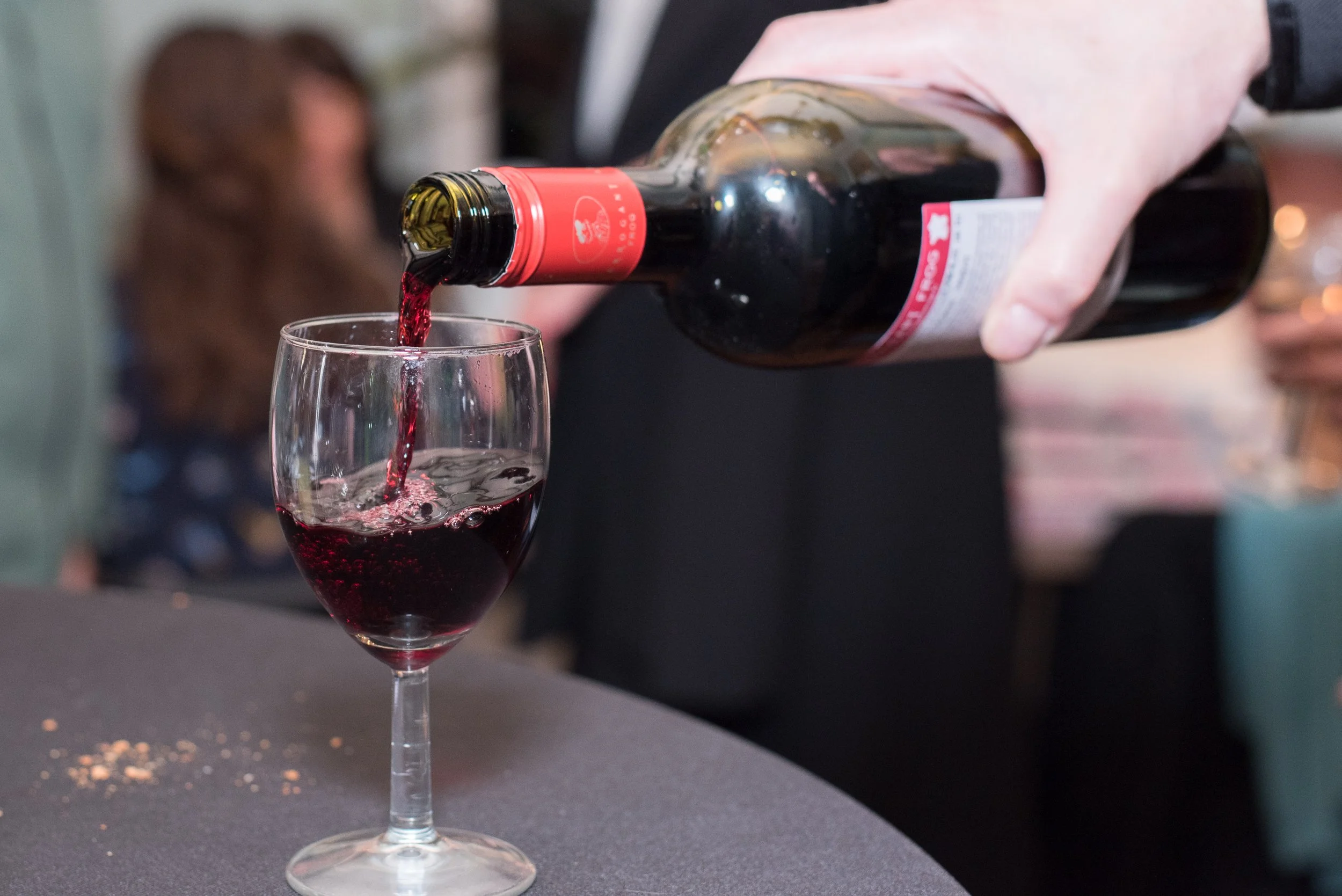 Detailopname van rode wijn die tijdens een receptie of evenement in een glas wordt geschonken.
