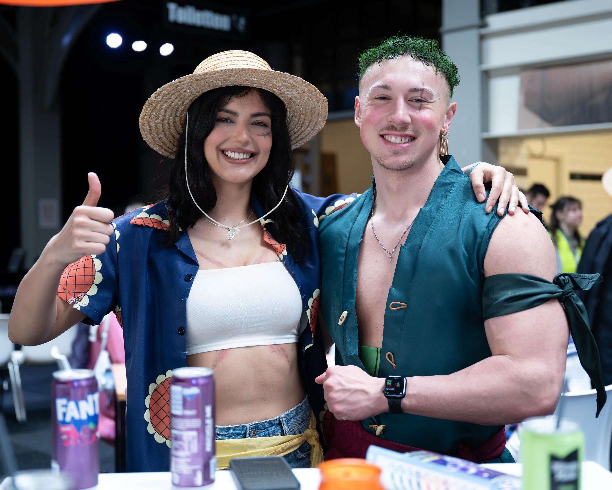 Professionele fotografie van een glimlachend stel in cosplay kostuums tijdens een conventie of evenement.