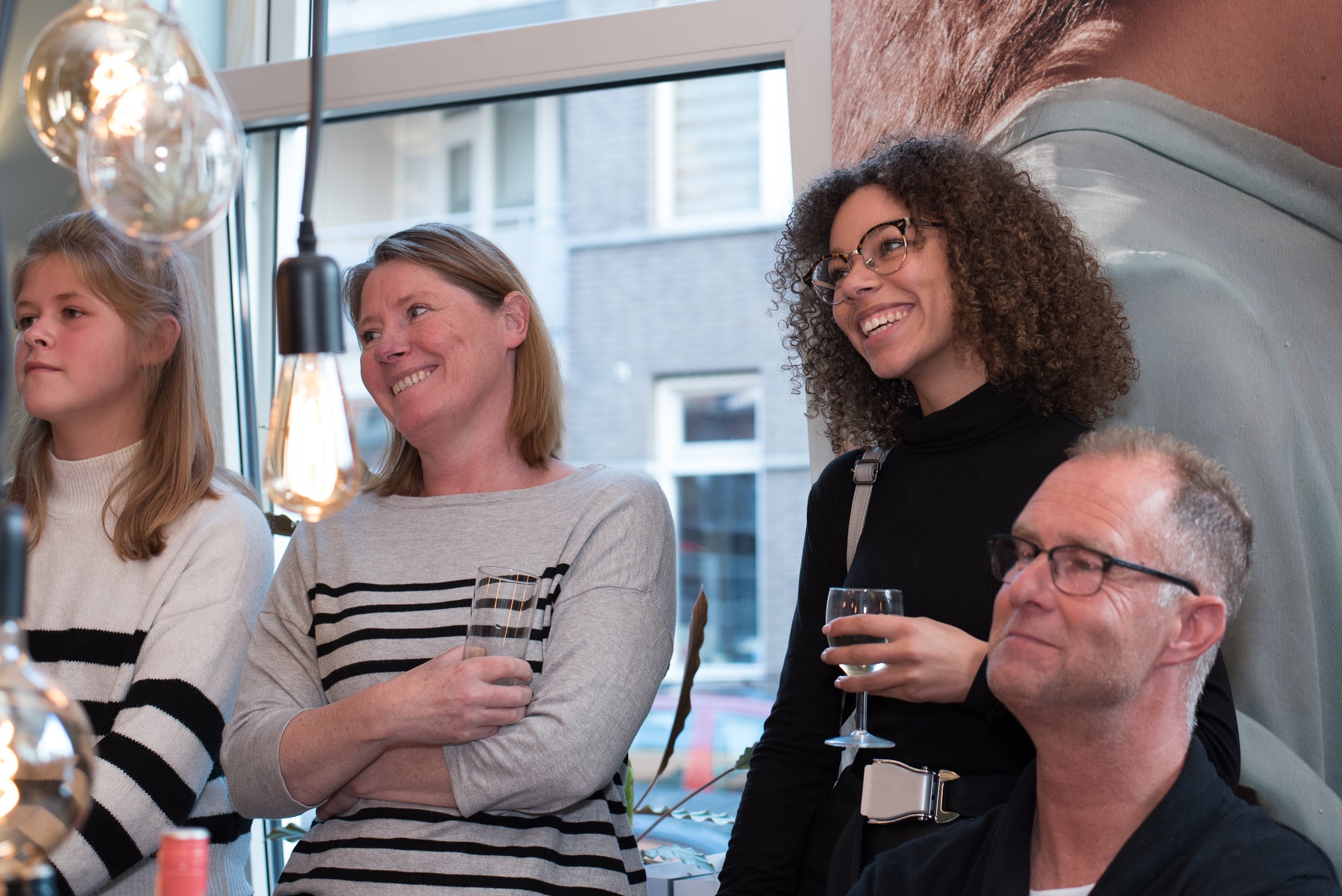 Sfeerimpressie van pratende gasten met een drankje in hun hand tijdens een receptie of feest.