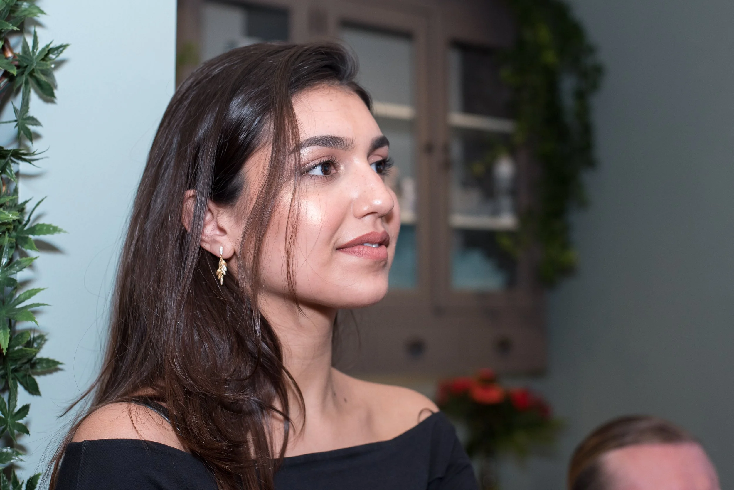 Portret van een jonge, donkerharige vrouw die aandachtig luistert tijdens een bijeenkomst.